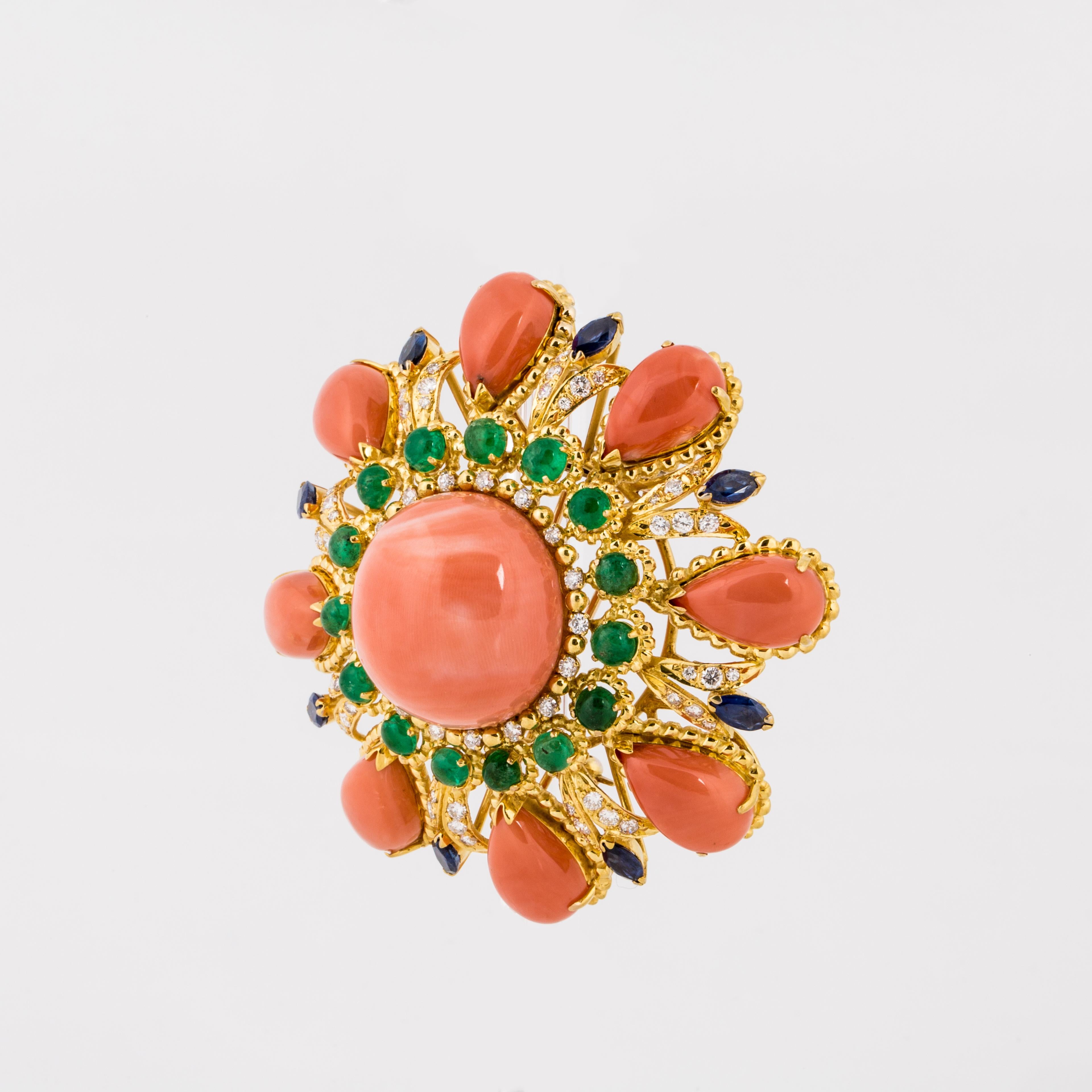 18K yellow gold gemset cluster brooch featuring a large 23.5 mm coral cabochon centerpiece, 8 coral teardrop shaped cabochons measuring approximately 15 x 9 x 5 mm, 15 emerald cabochons measuring approximately 4 mm each, 8 marquise sapphires