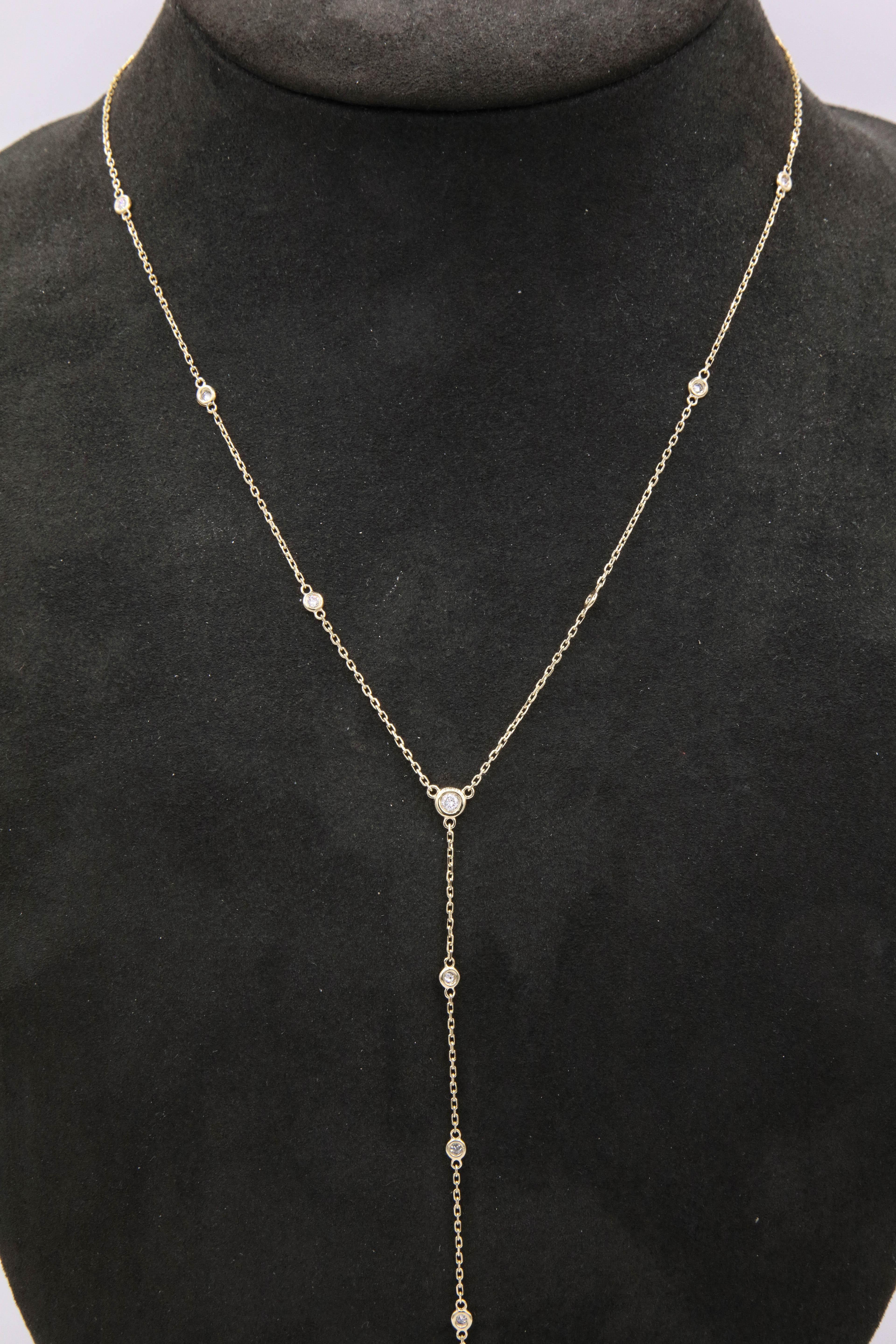 14K Yellow gold lariat necklace featuring 15 bezel set diamonds weighing 0.55 carats. 