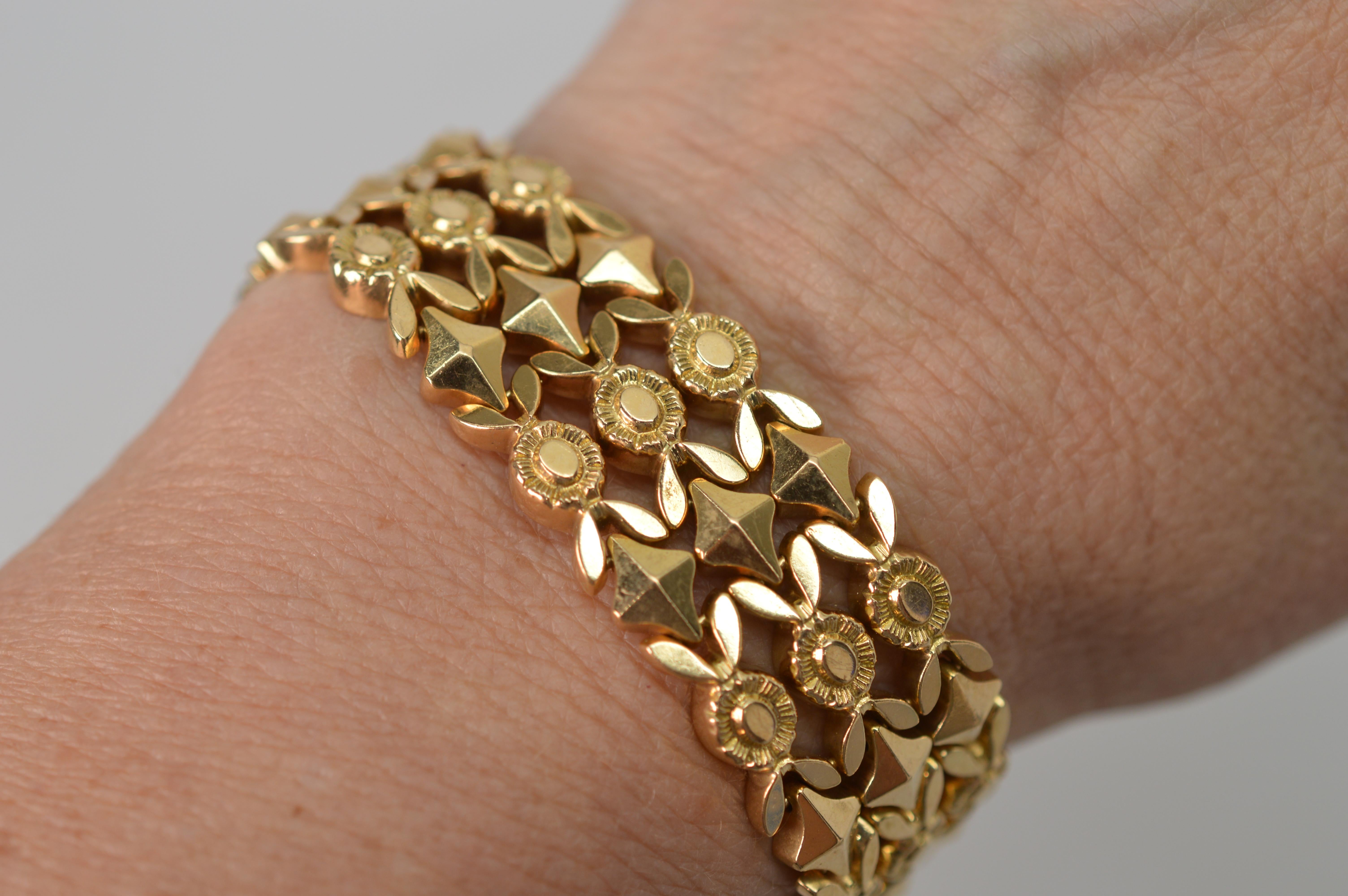 Timeless 1940's three row pyramid stud floral medallion link eighteen karat (18K) yellow gold bracelet . Flexible and well constructed, this classic piece measures 7-3/4 inch in length by 3/4 inch wide and is outfitted with box clasp and safety