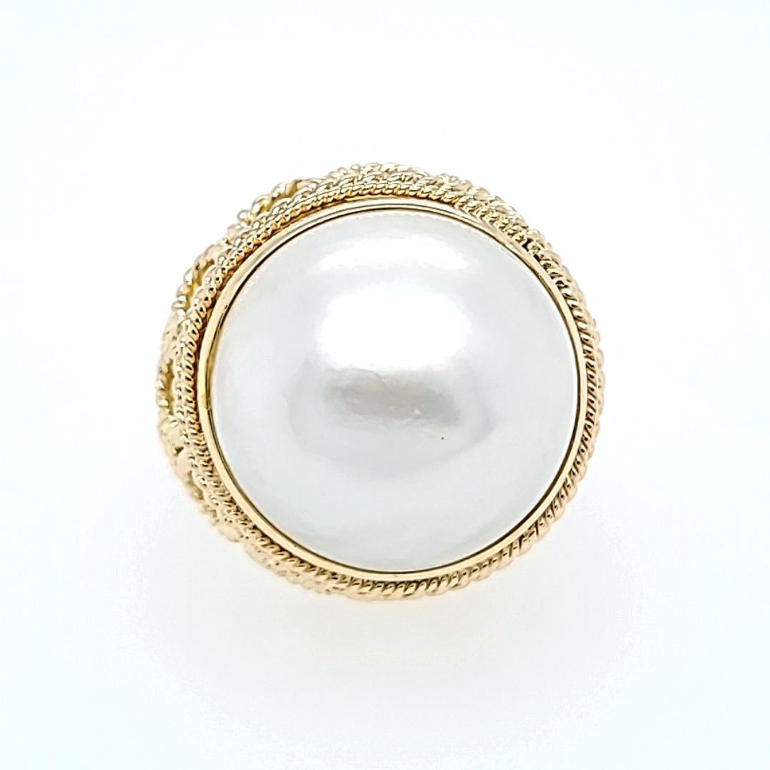 14 Karat Yellow Gold 17mm Round Mabe Pearl Ring Featuring Rope Texture Details. Finger Size 5.25; Purchase Includes One Sizing Service Prior to Shipping. Finished Weight Is 14 Grams.
