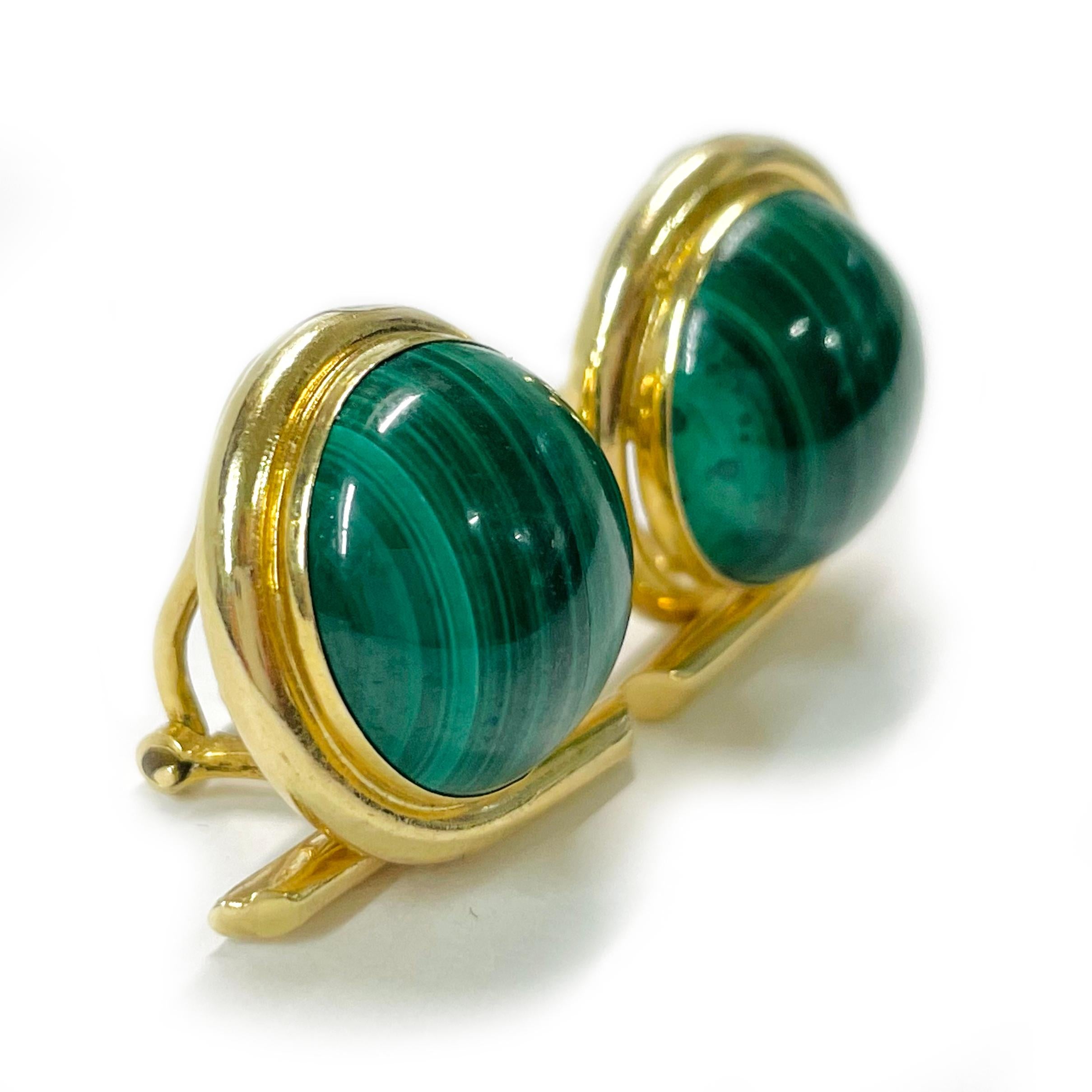 Yellow Gold Malachite Clip-On Earrings. The earrings feature a round Malachite cabochon set in a round 14 karat gold bezel with a bypass design. Stamped on the back of the bezel is PBD 14KT. The clip back is 18 karat yellow gold, stamped on the back