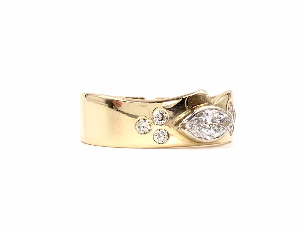 This unique slightly curvy 14k yellow gold band has a smooth and organic shape with a beautiful bezel set marquise diamond center with varnished round brilliant accent diamonds. Center diamond is approximately .65 carats at approximately G color,