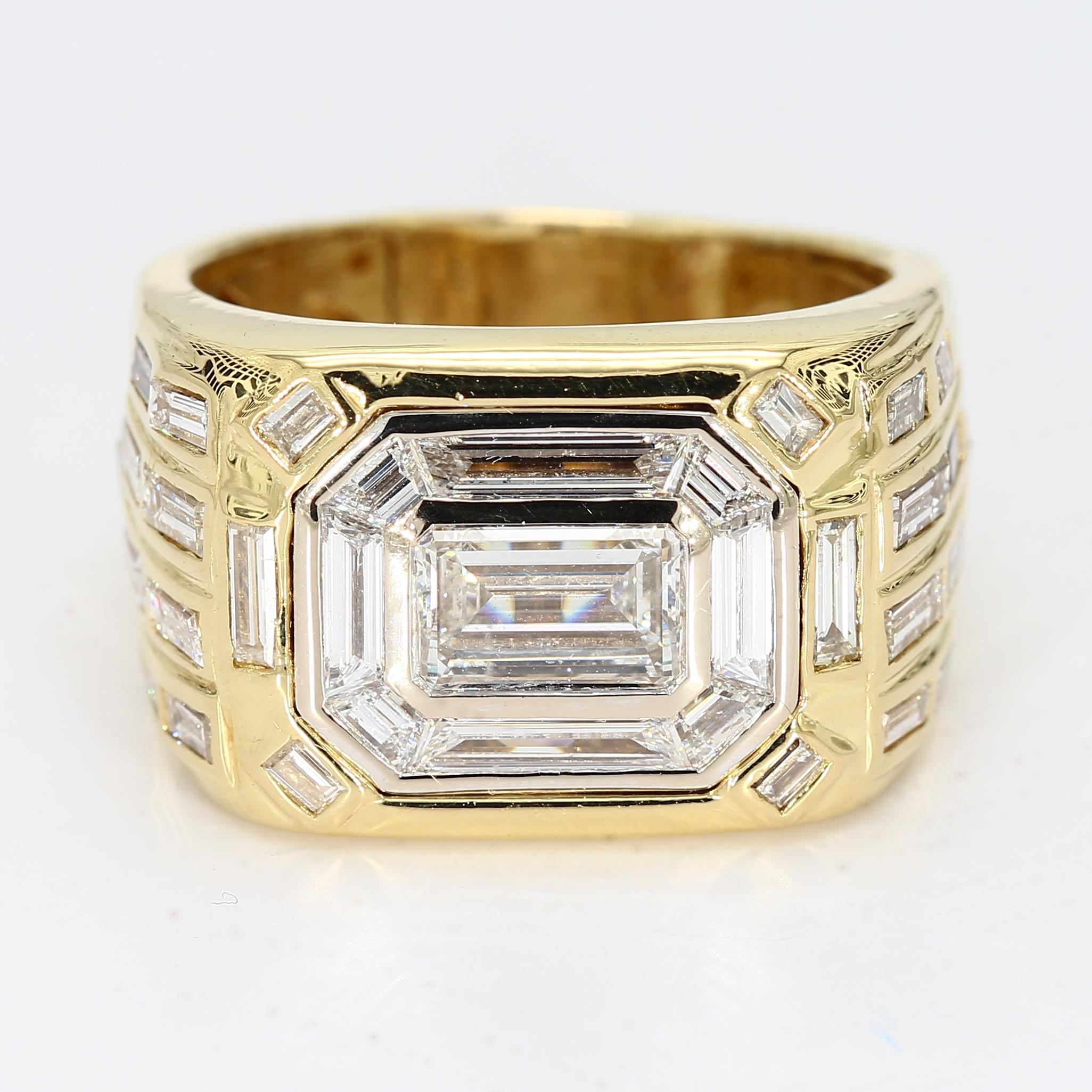 Il s'agit d'une bague pour homme en or jaune avec un diamant central de taille émeraude (7x5mm) entouré de diamants baguettes modifiés pour donner l'illusion que la pierre centrale est plus grande. En outre, l'anneau est orné d'une variété de
