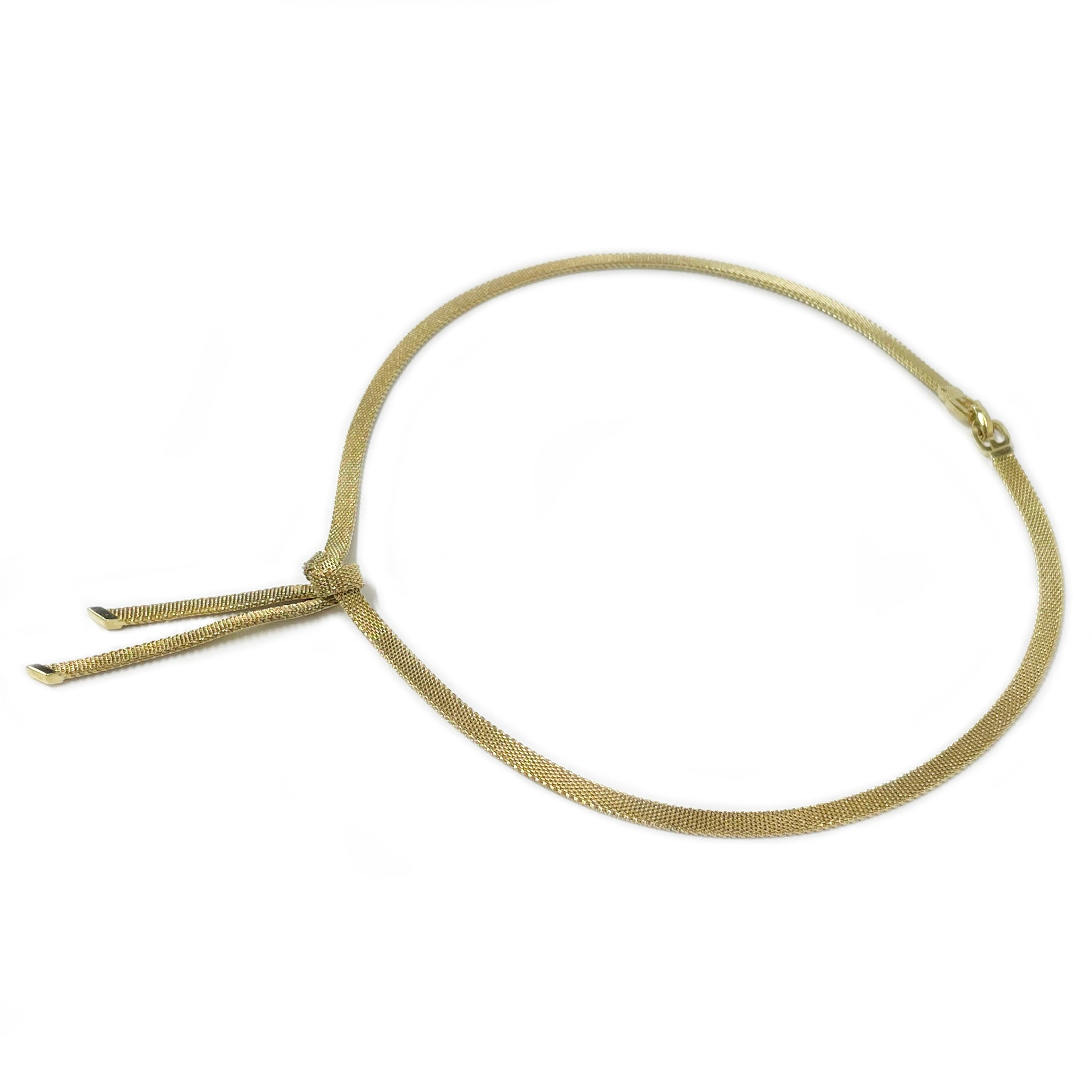 Collier à nœuds en or jaune 14 carats. Ce ravissant collier présente un nœud à la base avec deux morceaux de chaîne pendants avec un embout diagonal lisse et brillant sur chaque morceau. Le collier mesure 4 mm de large et 15,75