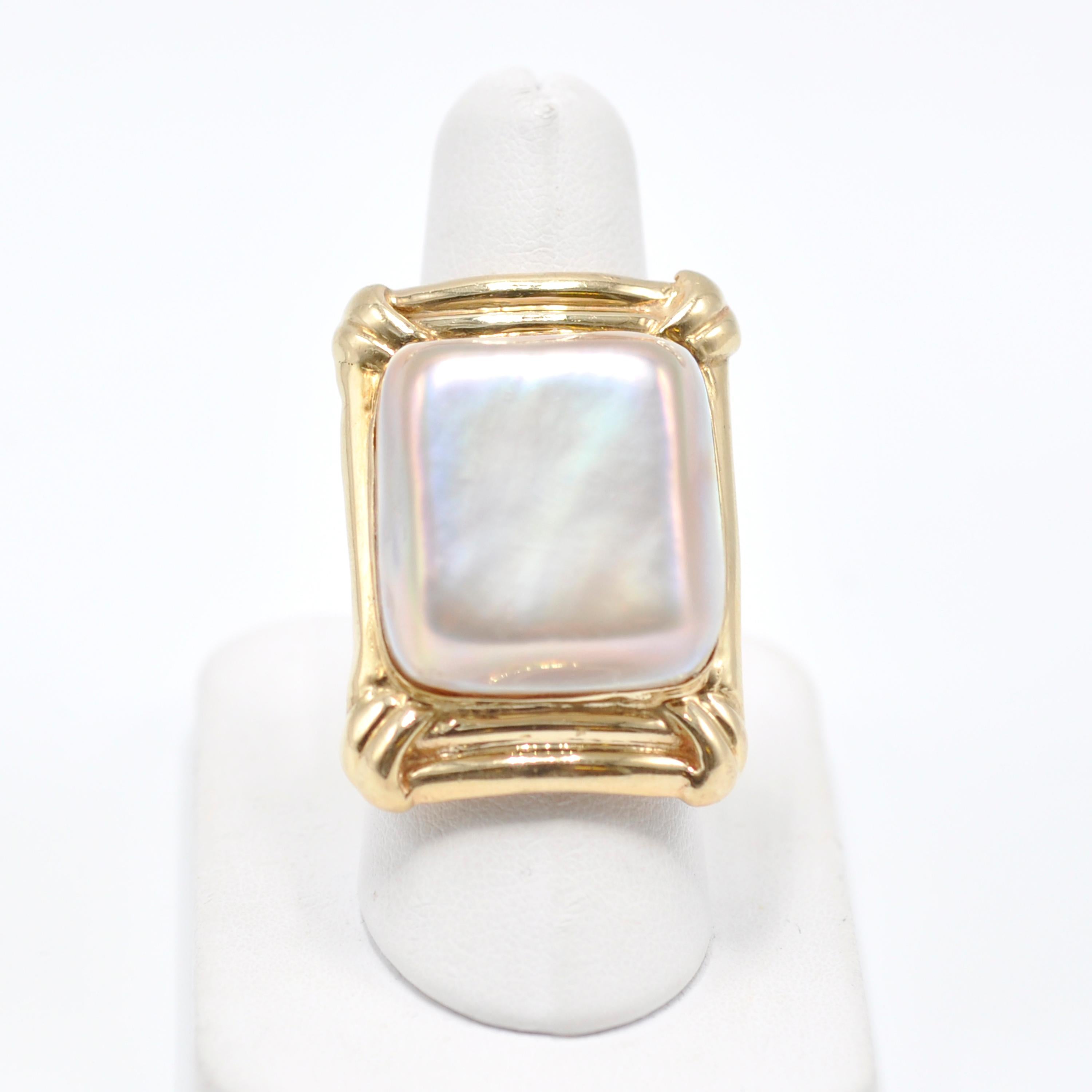 Our vintage 14 Karat Gold Mother of Pearl Ring is a bold statement added to any outfit. 

A large square cushion of Mother of Pearl sits atop a theatrical rectangular 14 karat gold setting. The irregularity of the design compliments the natural