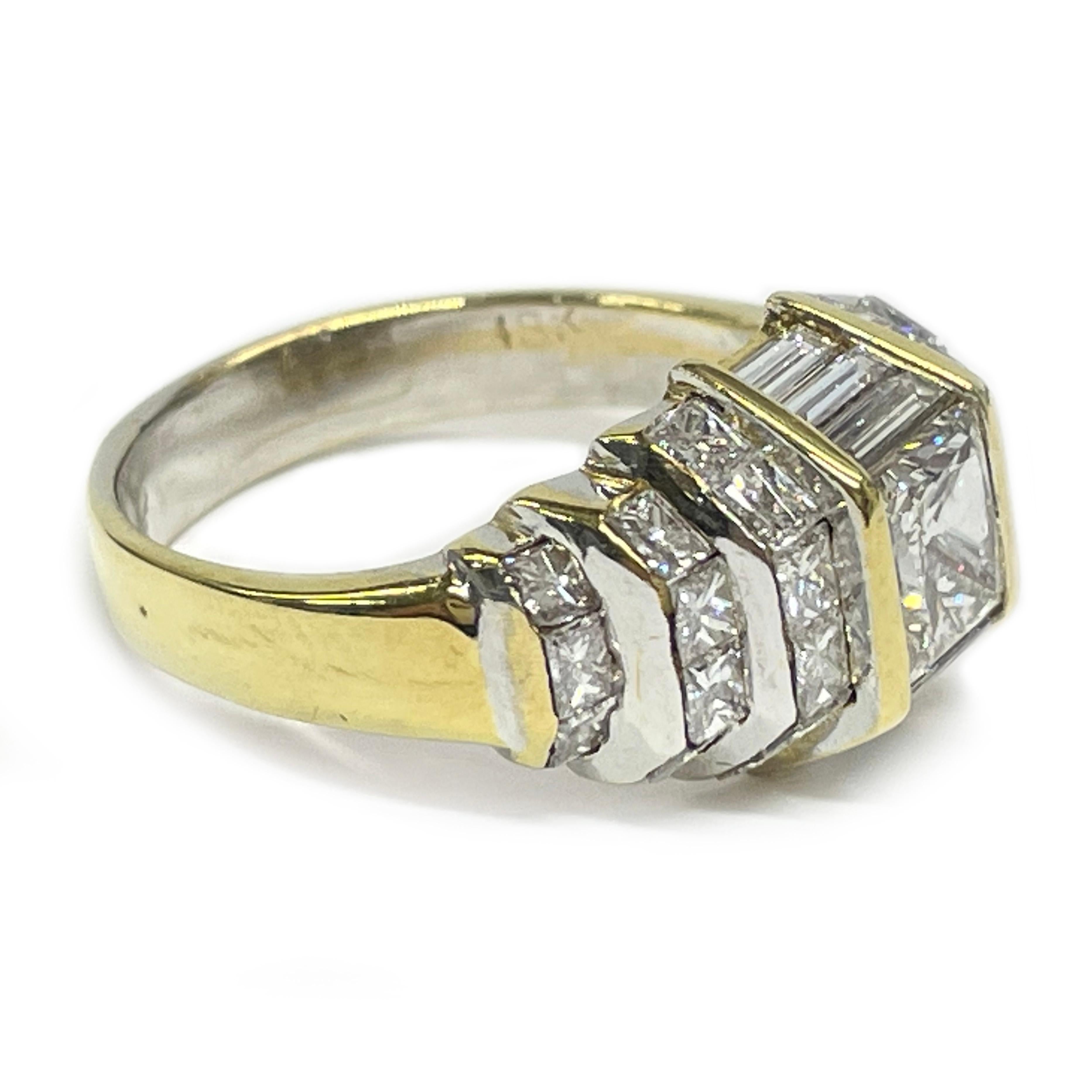 Cette bague en or jaune 18 carats à diamants multiples présente un superbe diamant de taille princesse serti en canal sur le dessus, flanqué de six diamants baguettes - trois en cascade sur le devant et trois le long de l'arrière. Les côtés de la