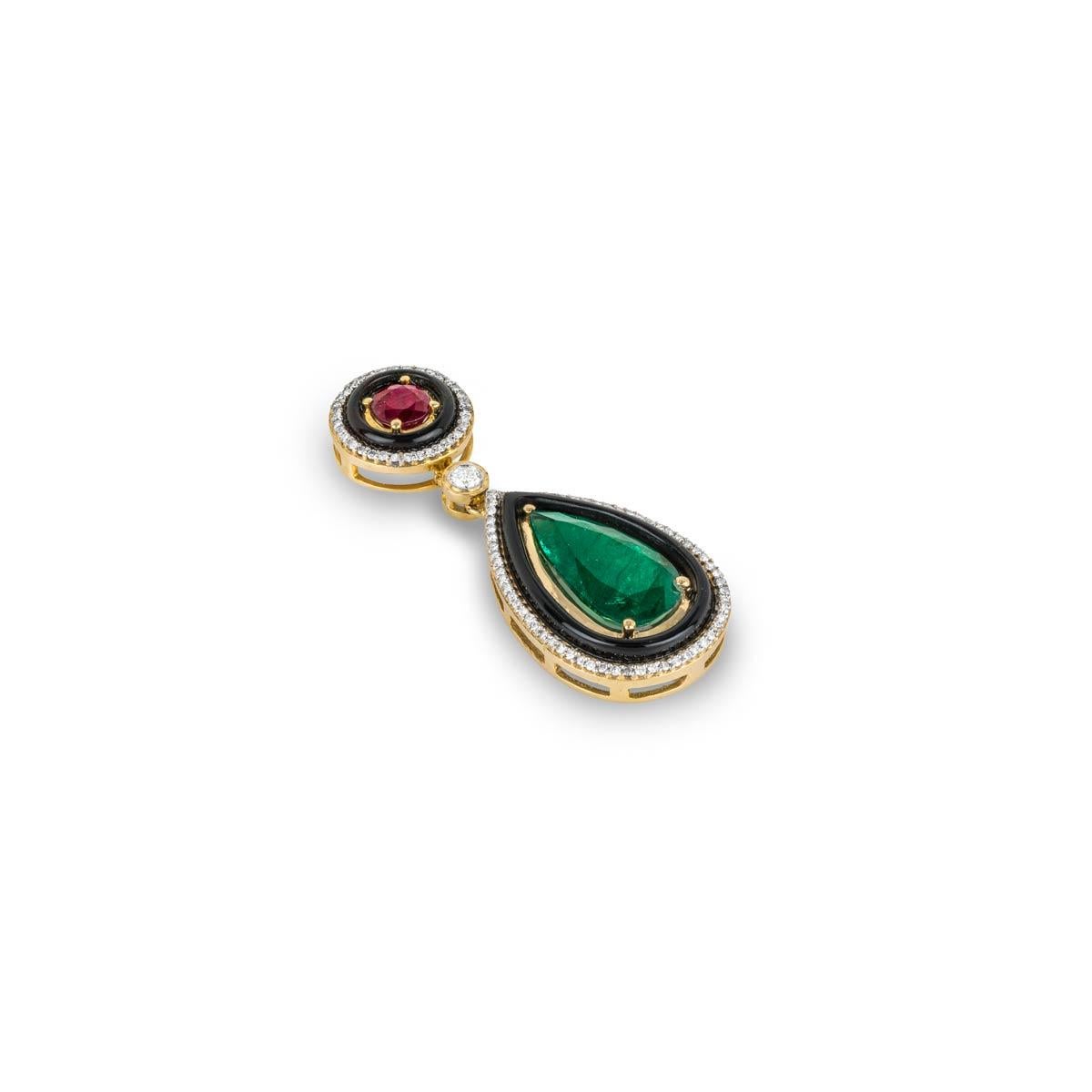An 18k yellow gold multi-gem pendant. The pendant is made up of a circular motif and a pear shaped motif joined together by a single round brilliant cut diamond. The first motif is set with a round cut ruby weighing 1.39ct and has a black onyx