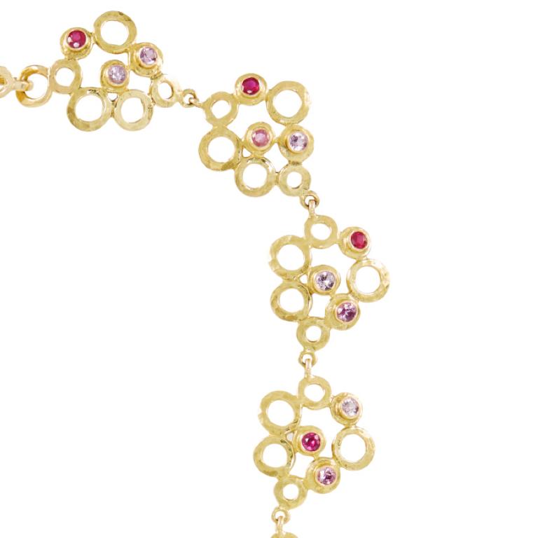 This Eastern inspired 18 carat yellow gold necklace with playful rings set with beautiful rubies, pink sapphires and diamonds, is truly special. Please note this item is made to order and a similar but not identical piece can be made. Allow four