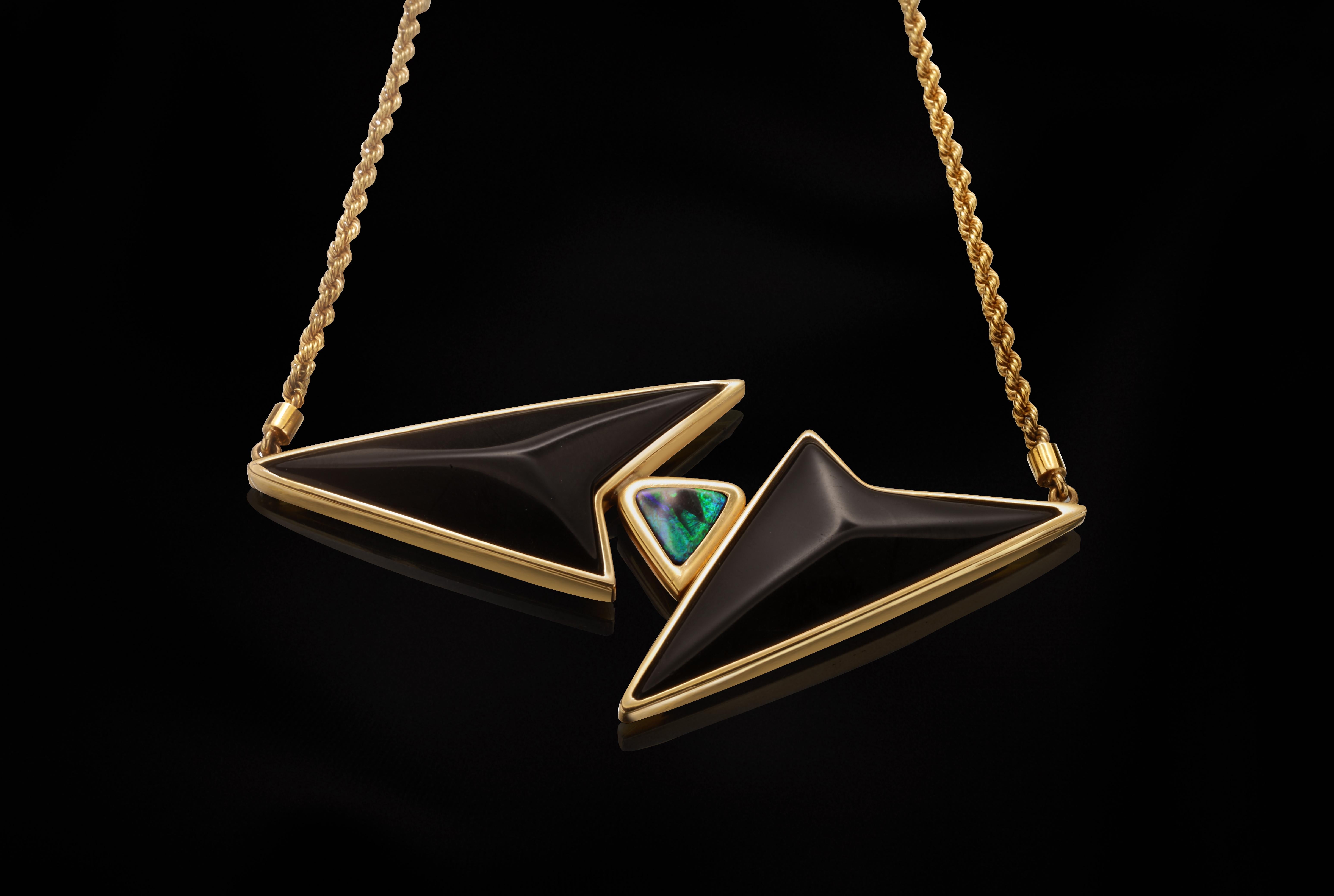 This necklace is handmade in 18 k yellow gold with two geometrically-cut pieces of onyx and a boulder Australian opal.
The main piece, with the two onyx and the opal, is held by a chain on each syde.
Gold clasp on the back part of the neck.
It is a