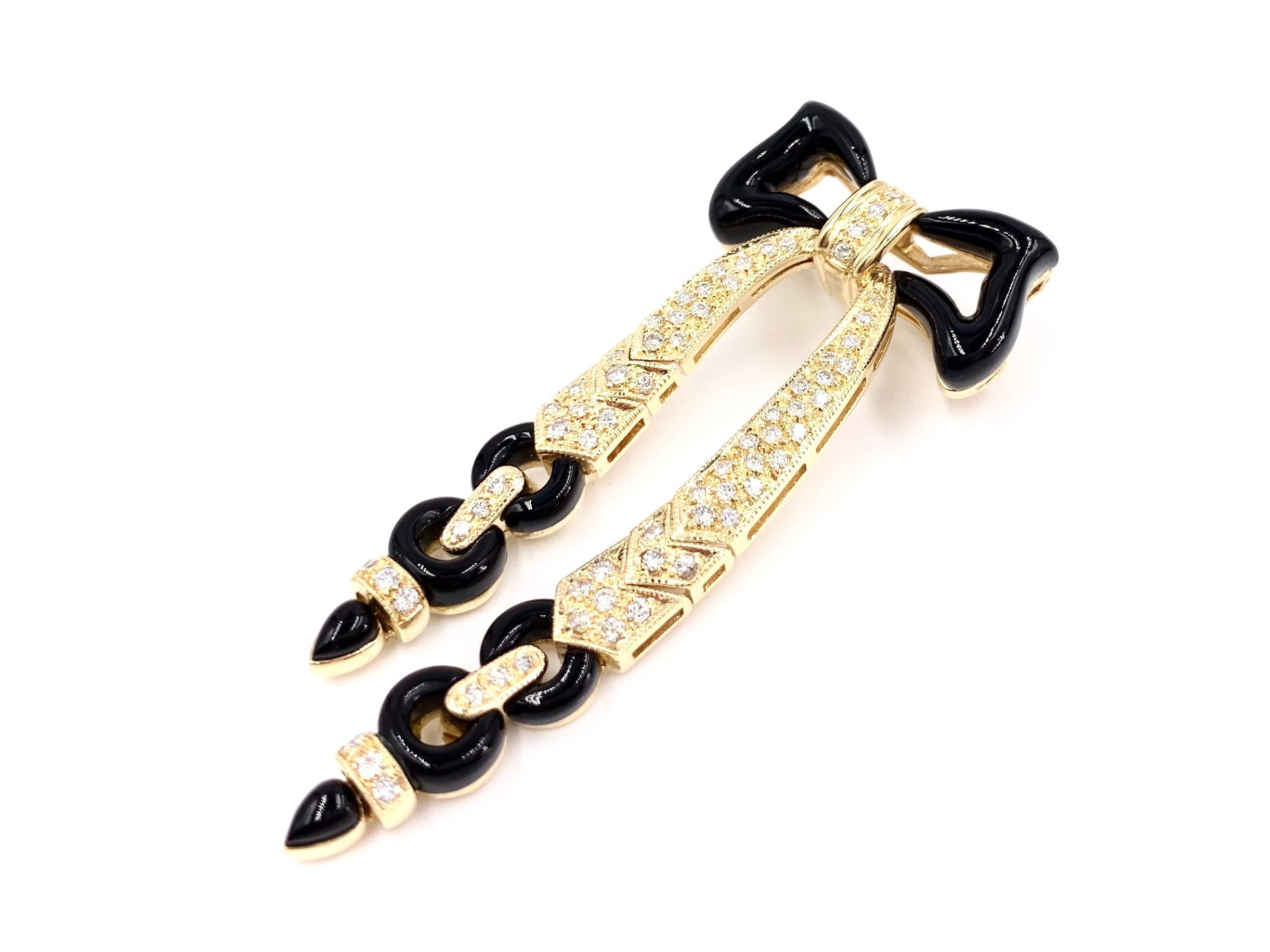 A beautiful 14 karat yellow gold Art Deco inspired bow brooch featuring polished, smooth black onyx and .97 carats of white diamonds. Diamond quality is approximately G color, VS2 clarity (near colorless, eye clean). Width of top section measures