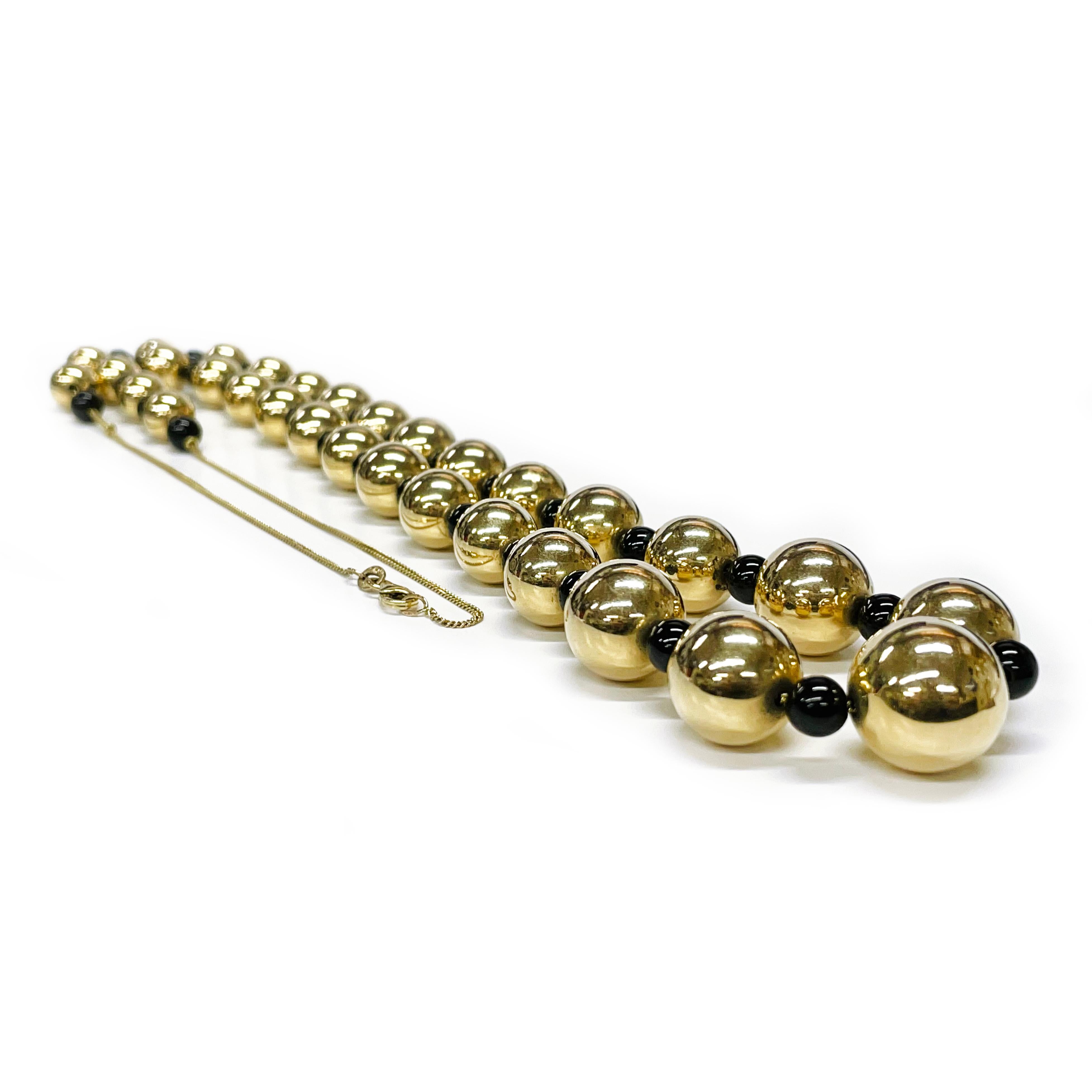 Collier en or jaune 14 carats et perles d'onyx. Le collier se compose d'un seul fil de perles rondes en or jaune de 9 à 15 mm et de 32 perles rondes en onyx de 6 mm. Trente et une perles d'or et trente-deux perles d'onyx sont montées sur une chaîne