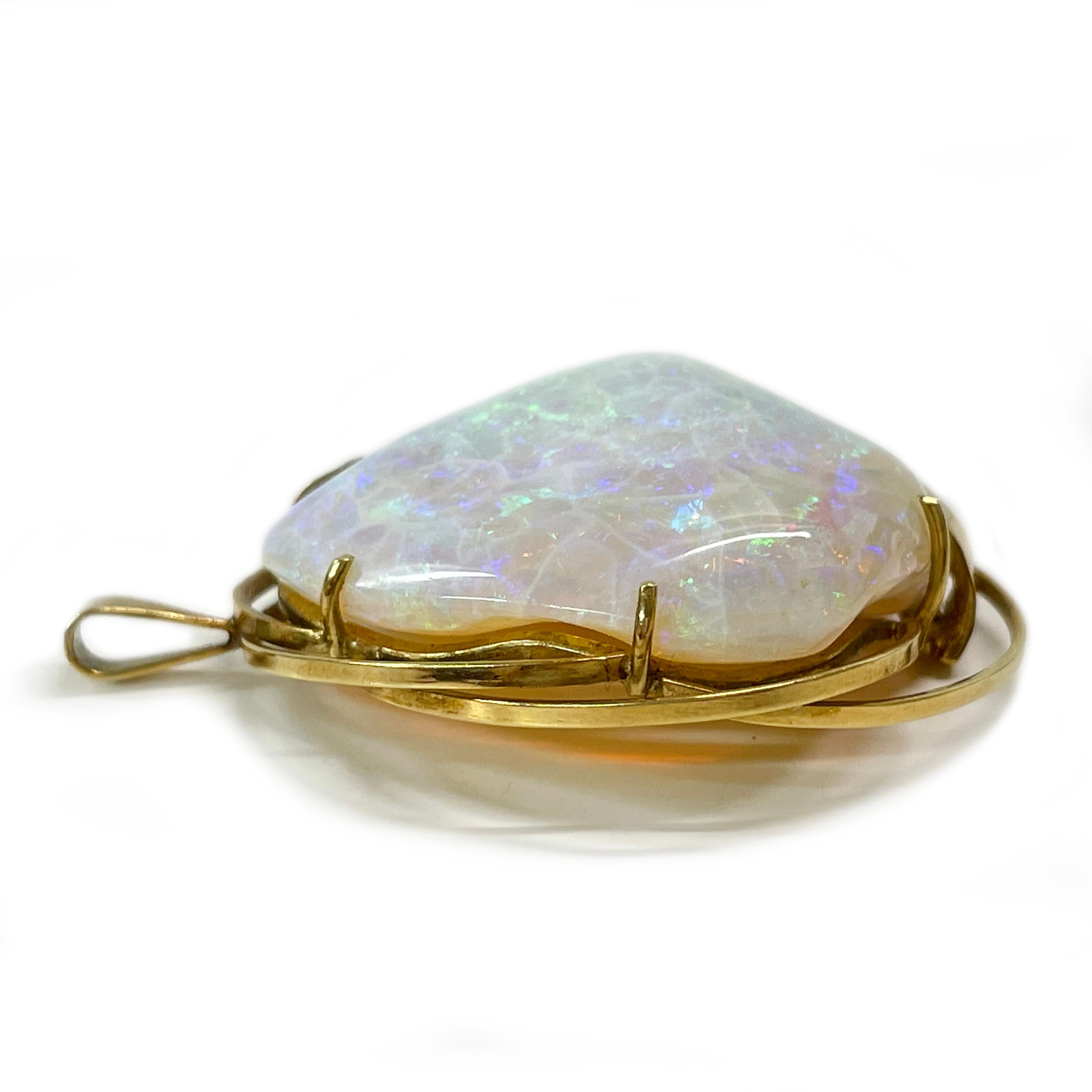 Tested 18 Karat Yellow Gold Opal Diamond Pendant. The pendant features a 32.43 x 28 x 61mm (46ct) opal prong-set on a handmade open bezel with multiple wire loops. There is a single gold strip on the front of the bezel that follows the form of the