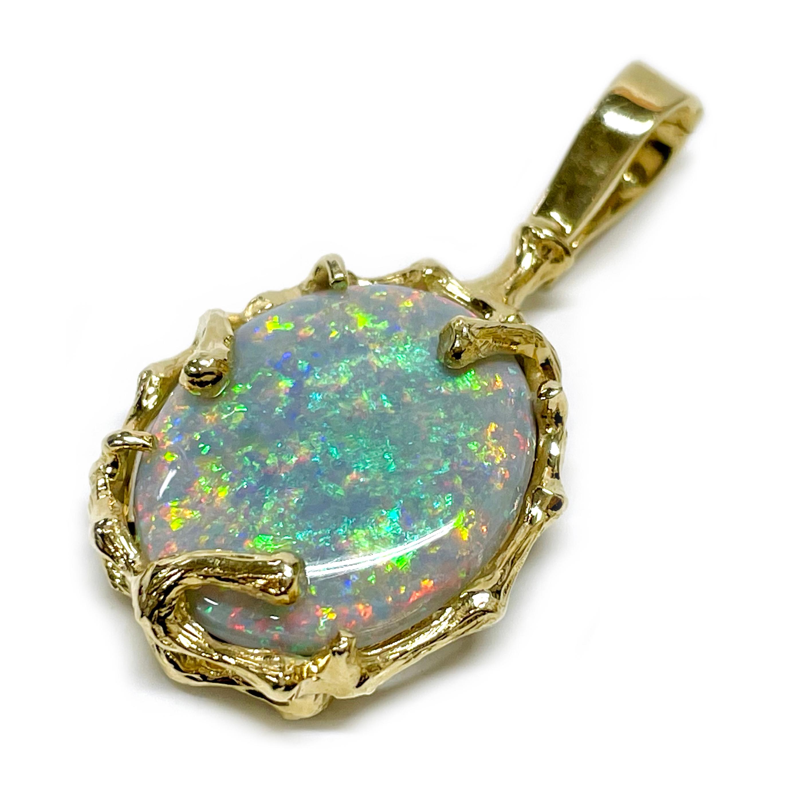 Electronically tested 18 Karat Yellow Gold Opal Pendant. The pendant has a featured oval opal set in an organic open bezel with branch-like prongs. The Opal measures 20.06 x 17.01mm and the pendant is 39.7mm high (including enhancer bail) 19.8mm