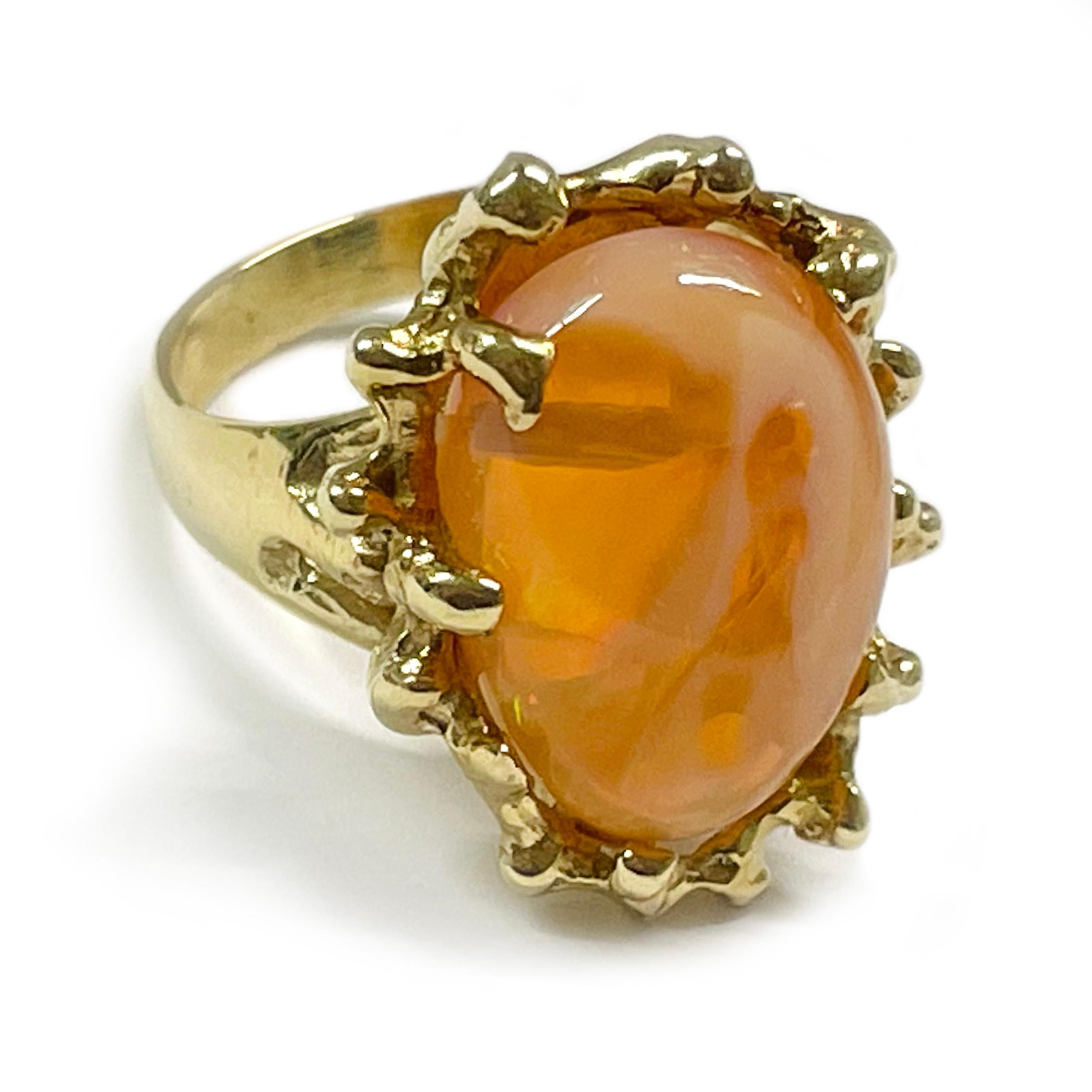 Yellow Gold Orange Mexican Opal Ring. The ring features a beautiful Mexican orange opal measuring 14.9 x 10.3mm. The opal has a vivid orange color with swirls of white and a play of green, red, and pink hues. The oval cabochon is set on a free-form