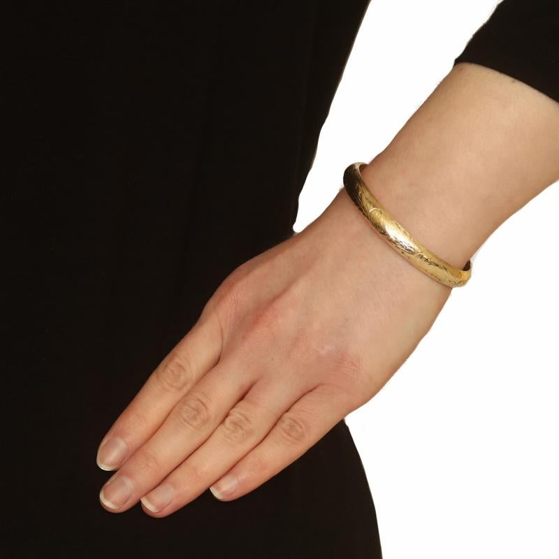 Metal Content: 14k Yellow Gold

Style: Oval Bangle
Fastening Type: Slide Clasp
Theme: Ferns
Features: Hollow construction with etched detailing

Measurements
Inner Circumference: 6 1/2