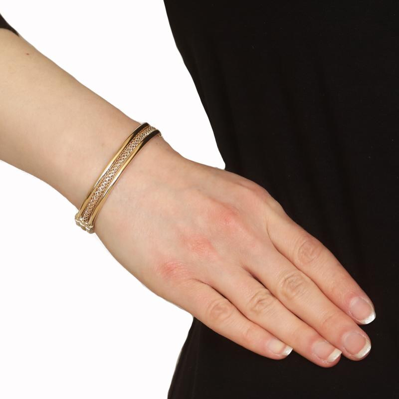 Metal Content: 14k Yellow Gold

Style: Oval Bangle
Fastening Type: Side Safety Clasp
Features: Hollow Construction, Smoothly Finished with Woven Mesh Center

Measurements
Inner Circumference: 6 1/2