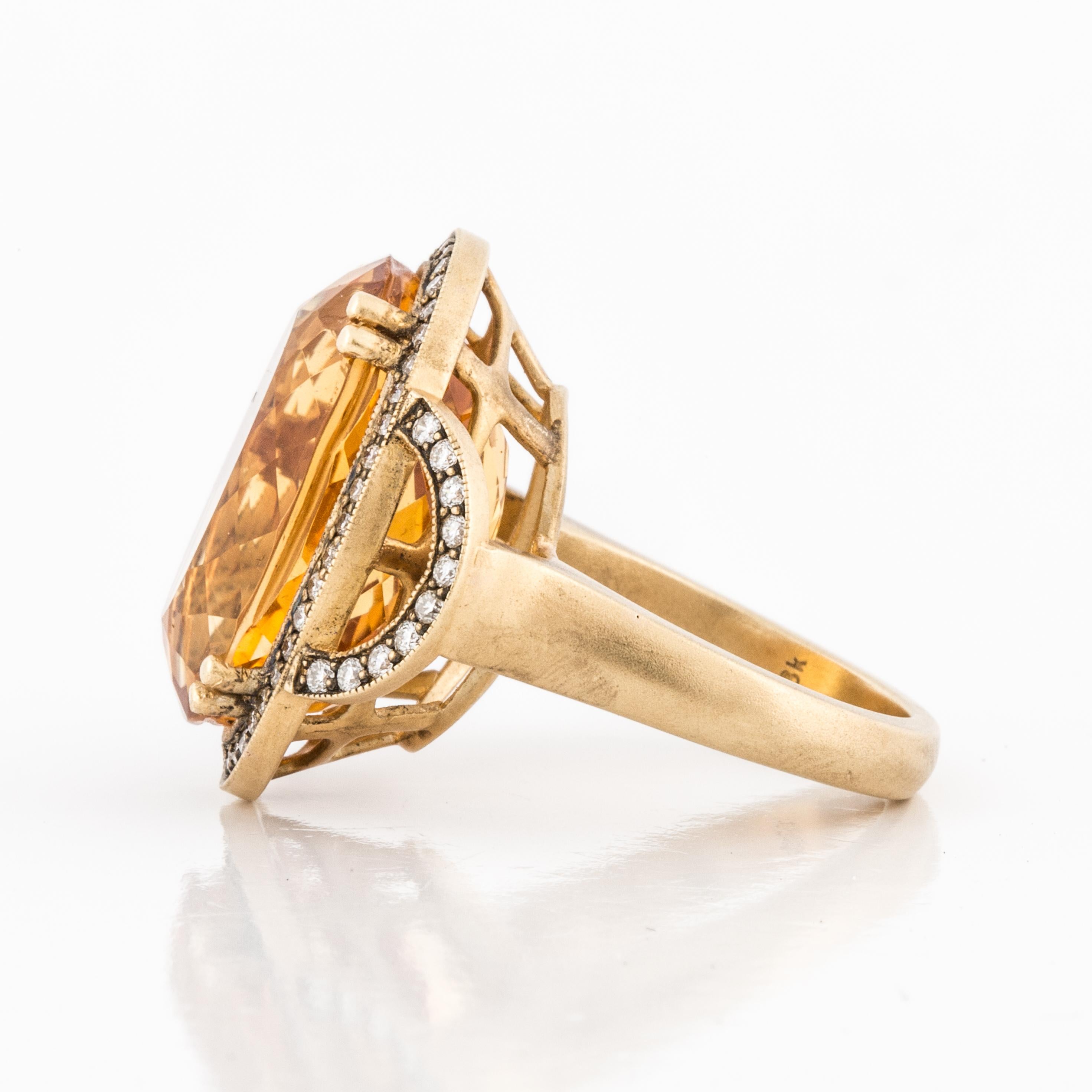 18K yellow gold ring featuring an oval citrine that totals 18 carats accented by sixty-five (65) round brilliant-cut diamonds that total 0.65 carats.  The gold has a soft matte finish. Large presentation area, measuring 1 3/16 inches by 15/16 inches.