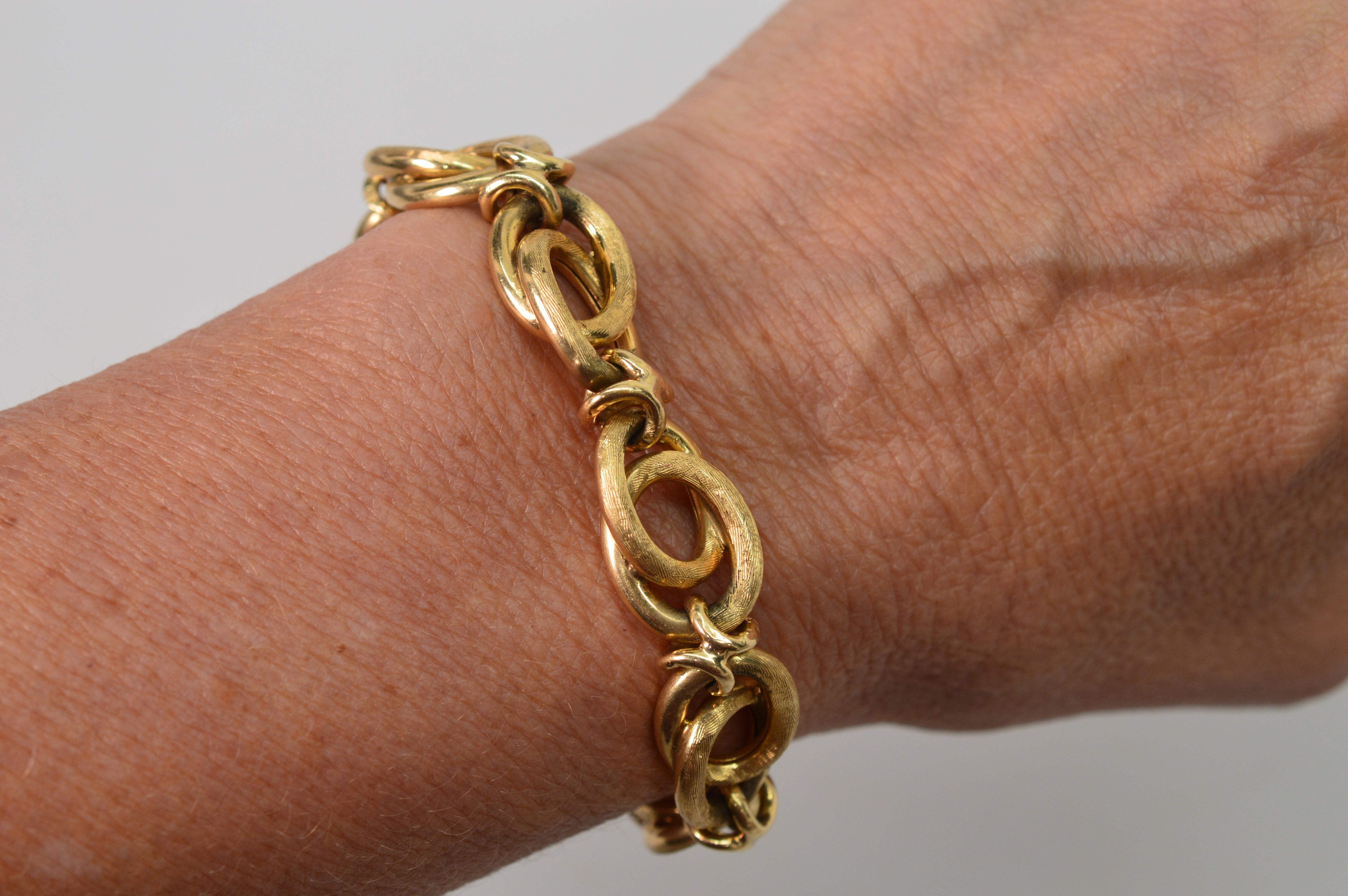 A mix of textured and smooth finishes create interest on this versatile 1950's bracelet of generous oval fourteen karat yellow gold. Outfitted with slide closure and safety clasp this fancy 7-3/4 inch bracelet has an inside circumference of 7-1/4