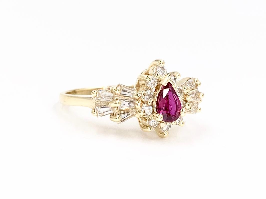 A 14 karat yellow gold vintage pear shape ruby and white diamond ring. Well saturated ruby has a pure red hue (not pink) and is approximately .50 carats surrounded by a halo of 10 round brilliant diamonds and flanked by 10 baguette diamonds.