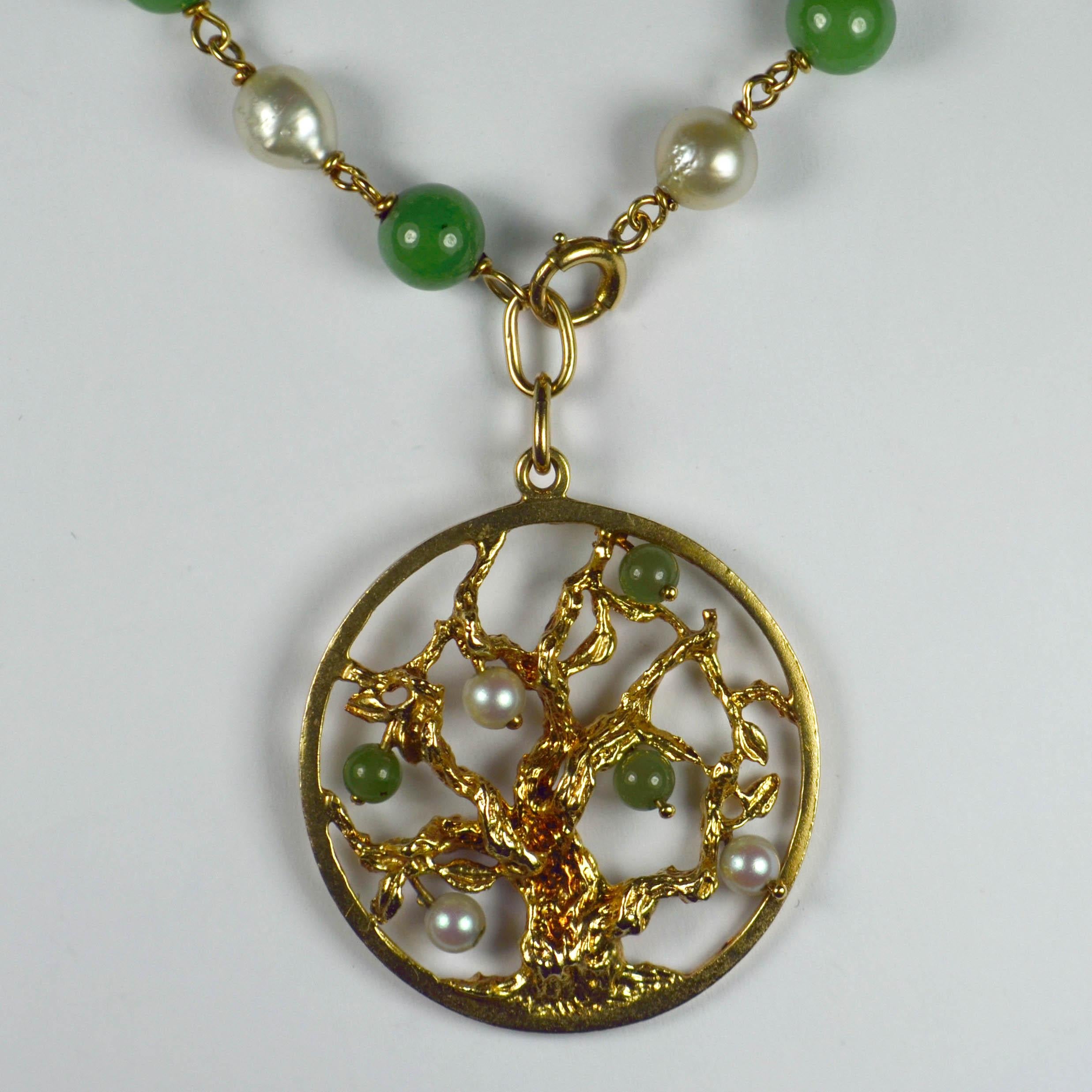 A 14 karat yellow gold charm bracelet with a dangling charm pendant designed as a tree of life set with green nephrite jade beads and white cultured pearls. The bracelet is set with 14 alternating beads of nephrite and white cultured pearl with an