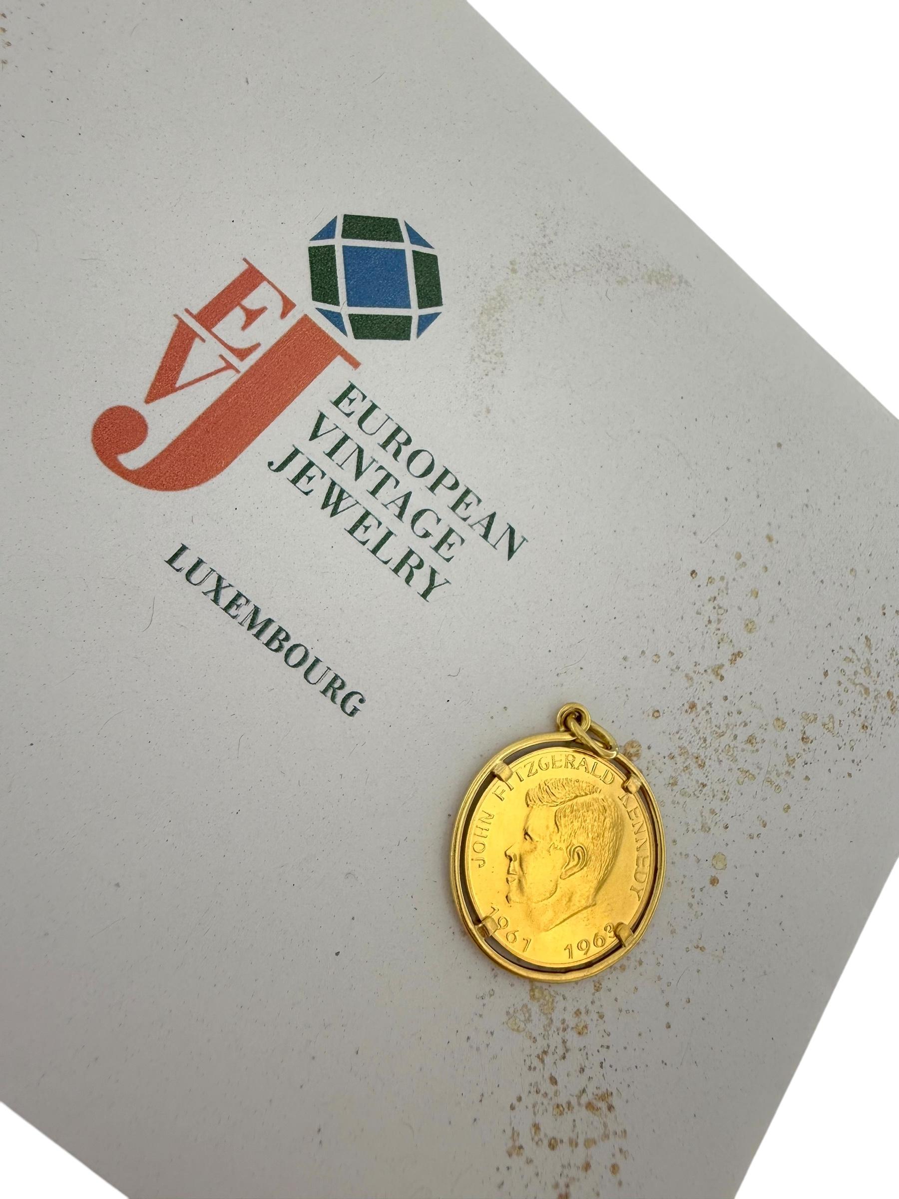 Ce **pendentif en or jaune** est une pièce historique et distinguée, qui présente une **pièce authentique de John Fitzgerald Kennedy** sertie dans un **cadre en or 18kt**. La pièce elle-même est fabriquée en **21kt gold**, ce qui ajoute à sa rareté