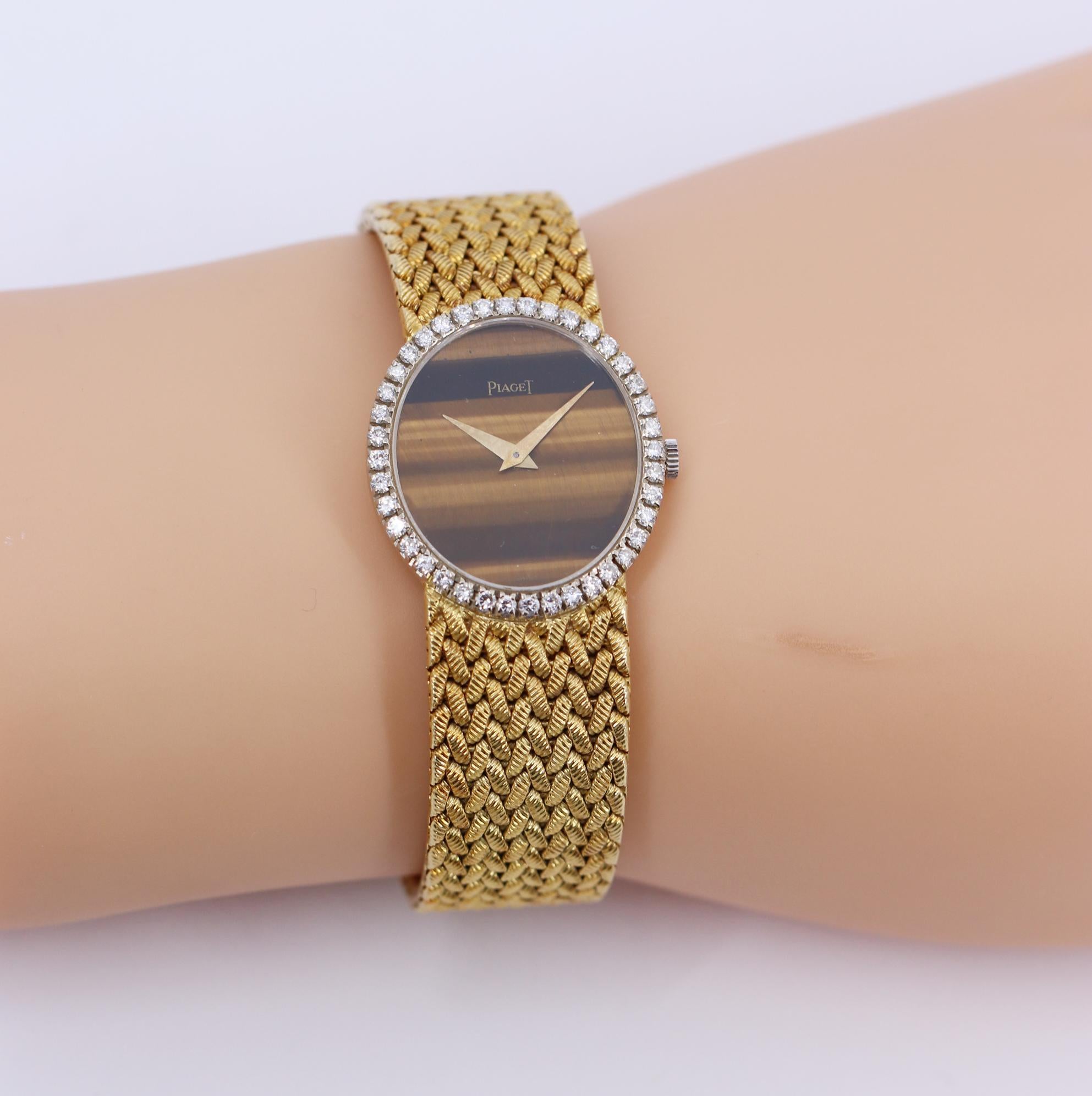 A ladies, 18K yellow gold Piaget wristwatch centered around a tiger's eye dial measuring 23mm by 20mm. Surrounding the dial are 40 round brilliant cut diamonds weighing 1ct total approximate weight, of overall F/G color and VVS2/VS1 clarity. The