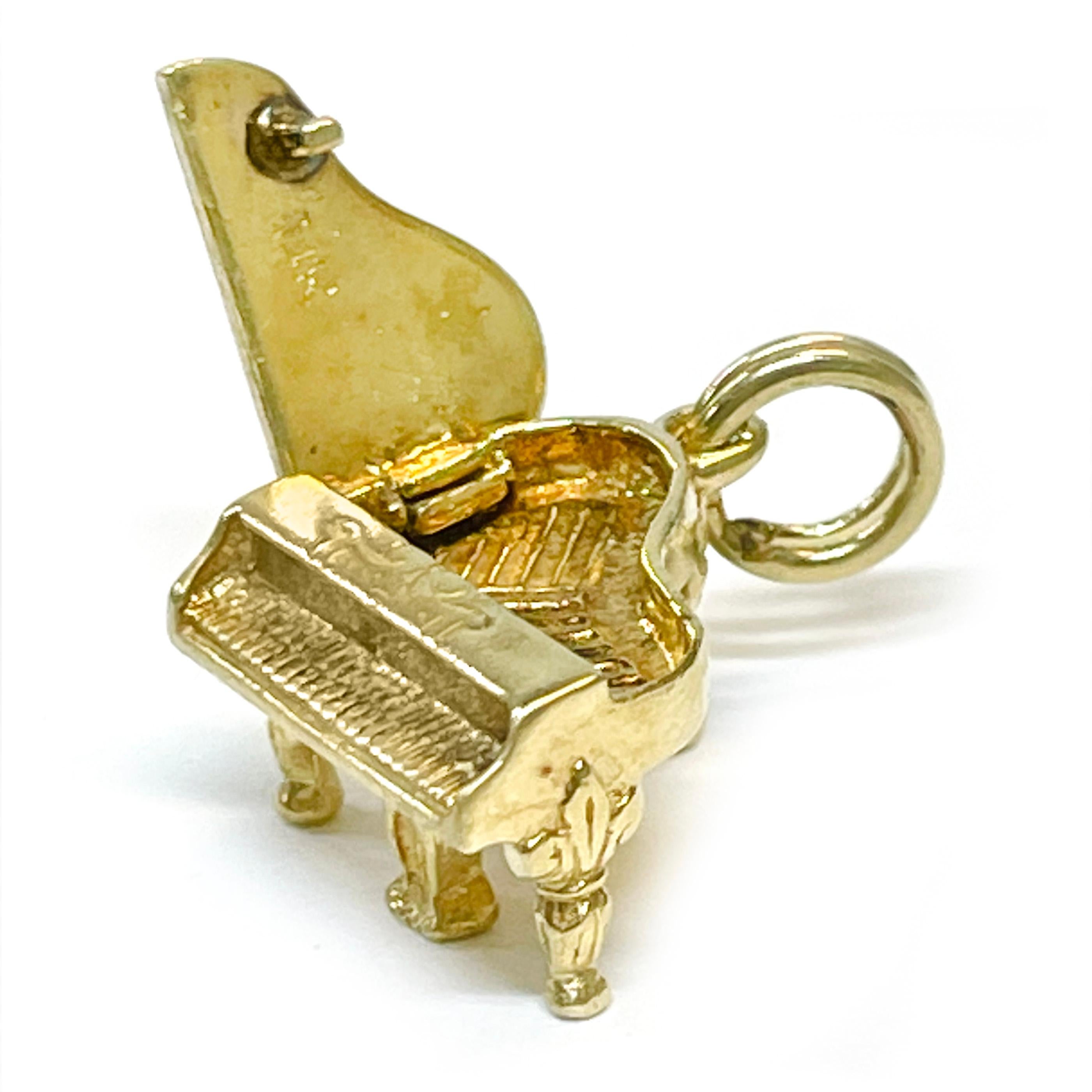 14 Karat Yellow Gold Piano Charm Pendant. This adorable piano features lovely details with fleur de lis designs on the legs, defined keys and a top that opens to show the inside of the piano. The pendant measures 9.2mm high x 12.8mm wide x 12.8mm