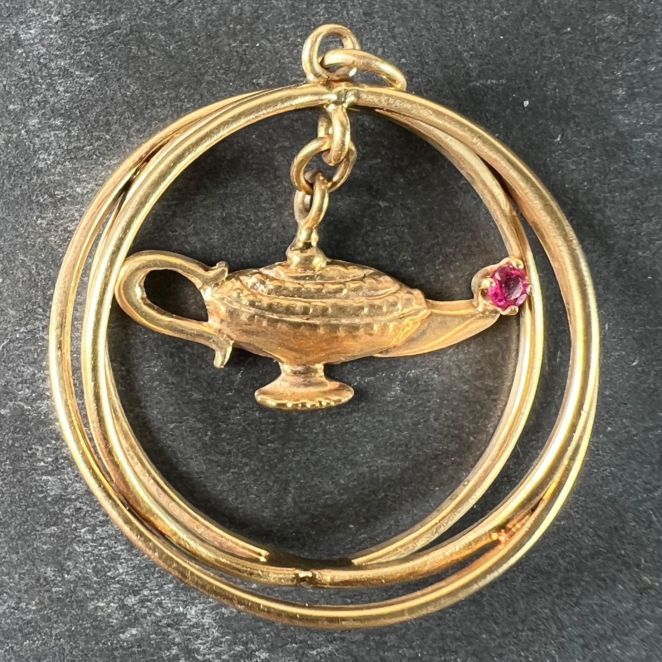 Un grand pendentif à breloques en or jaune 14 carats conçu comme trois anneaux entrelacés suspendant une lampe de génie cinétique avec un rubis rouge serti dans le bec. Le poids du rubis est estimé à 0,10 carats. Estampillé 14K.

Dimensions : 3.3 x