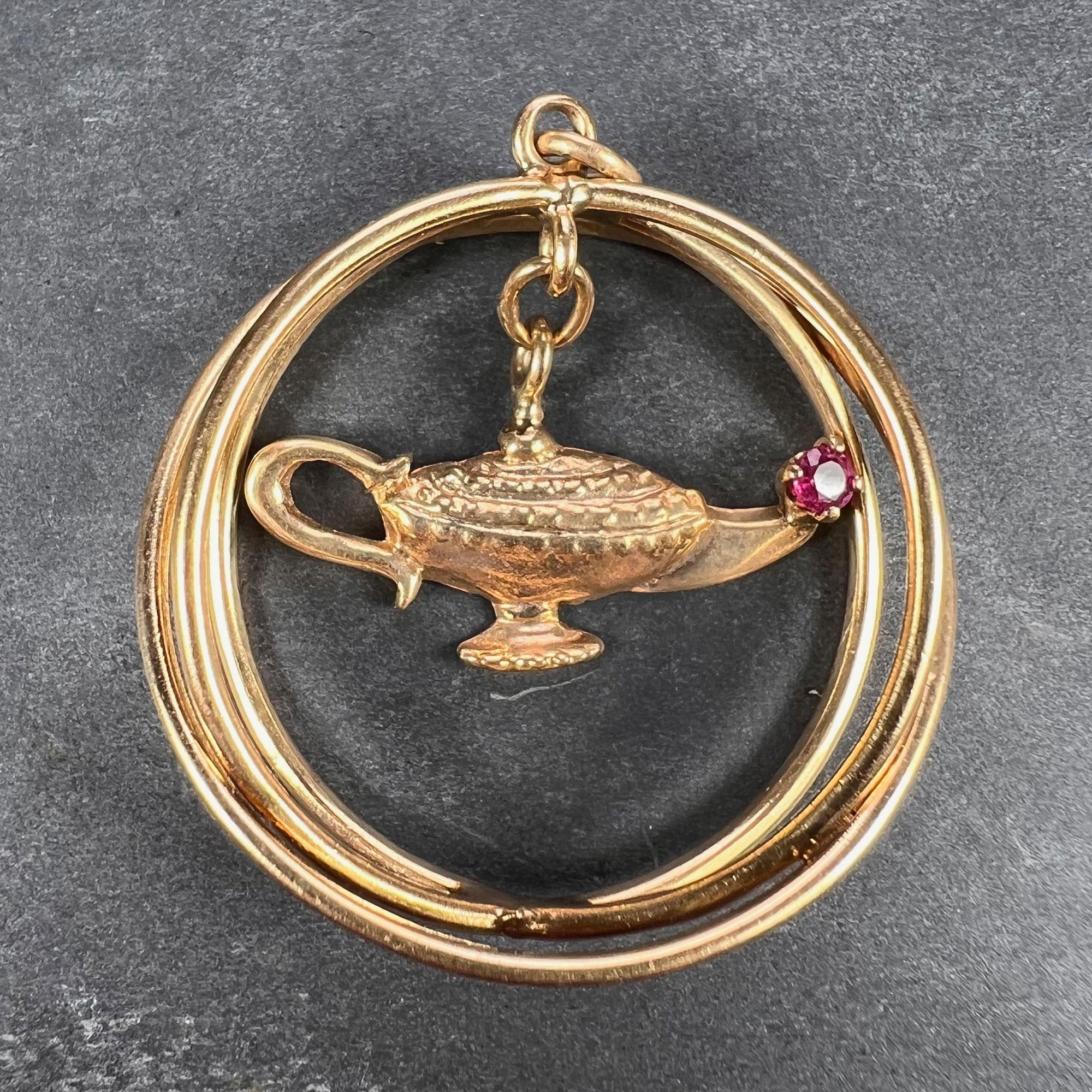 A large 14 karat yellow gold charm pendant designed as three interlaced hoops suspending a kinetic genie lamp with a red ruby set in the spout. The ruby is estimated to weigh 0.10 carats. Stamped 14K.

Dimensions: 3.3 x 3.8 cm
Weight: 7.93 grams