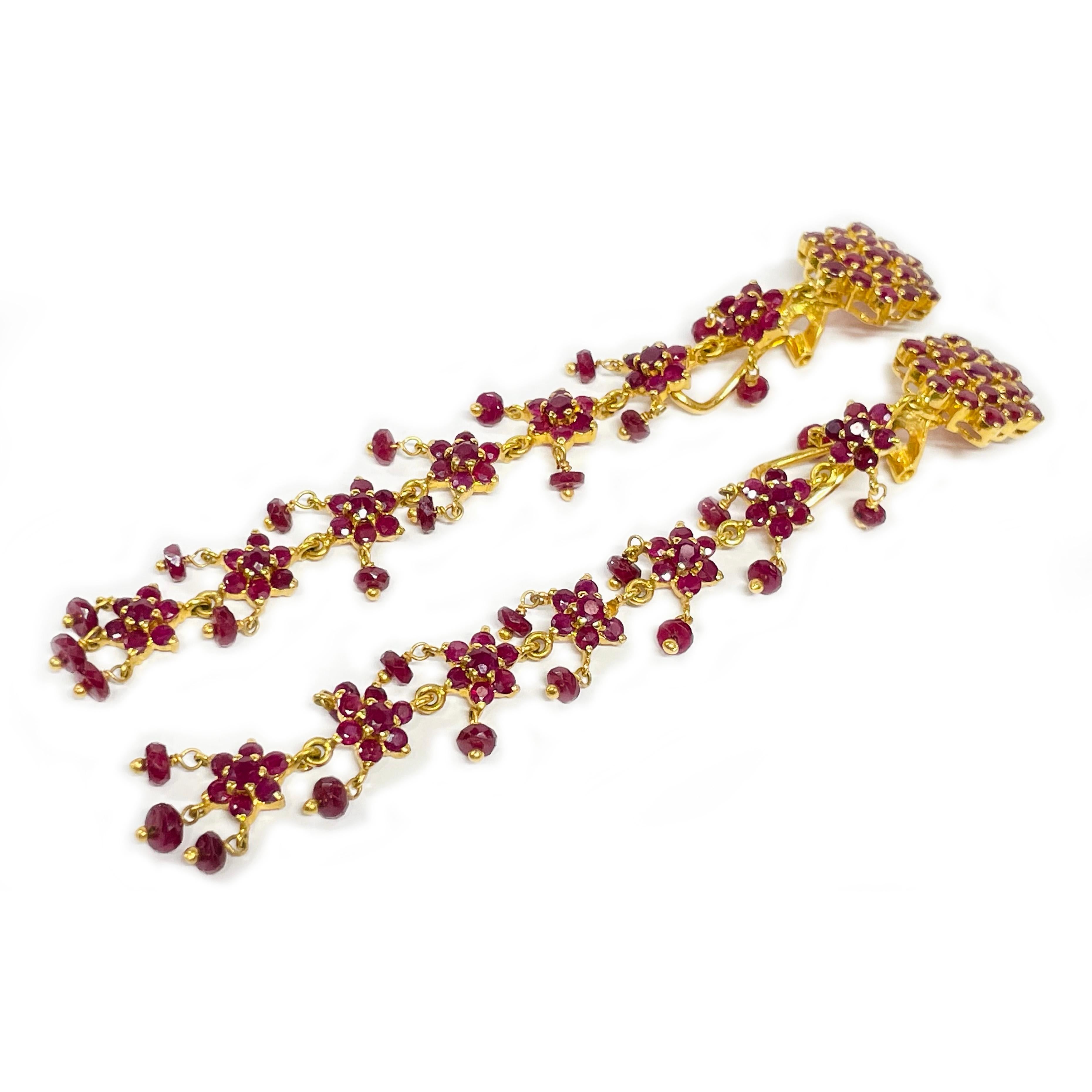 Yellow Gold Ruby Clip-On Dangle Earrings.

Each earring showcases an oval emerald cabochon secured with two double prongs, surrounded by nine round prong-set diamonds encircling the bezel, complemented by gold wing-like swooshes that extend outward.