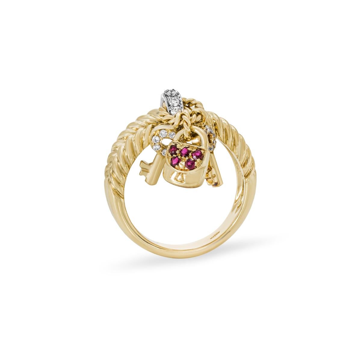 A charming 18k yellow gold ruby and diamond ring. The ring comprises of a crossover rope design with a diamond set loop in the centre. Attached to the loop are 2 diamond set key charms and a ruby set lock charm. The 5 rubies have an approximate