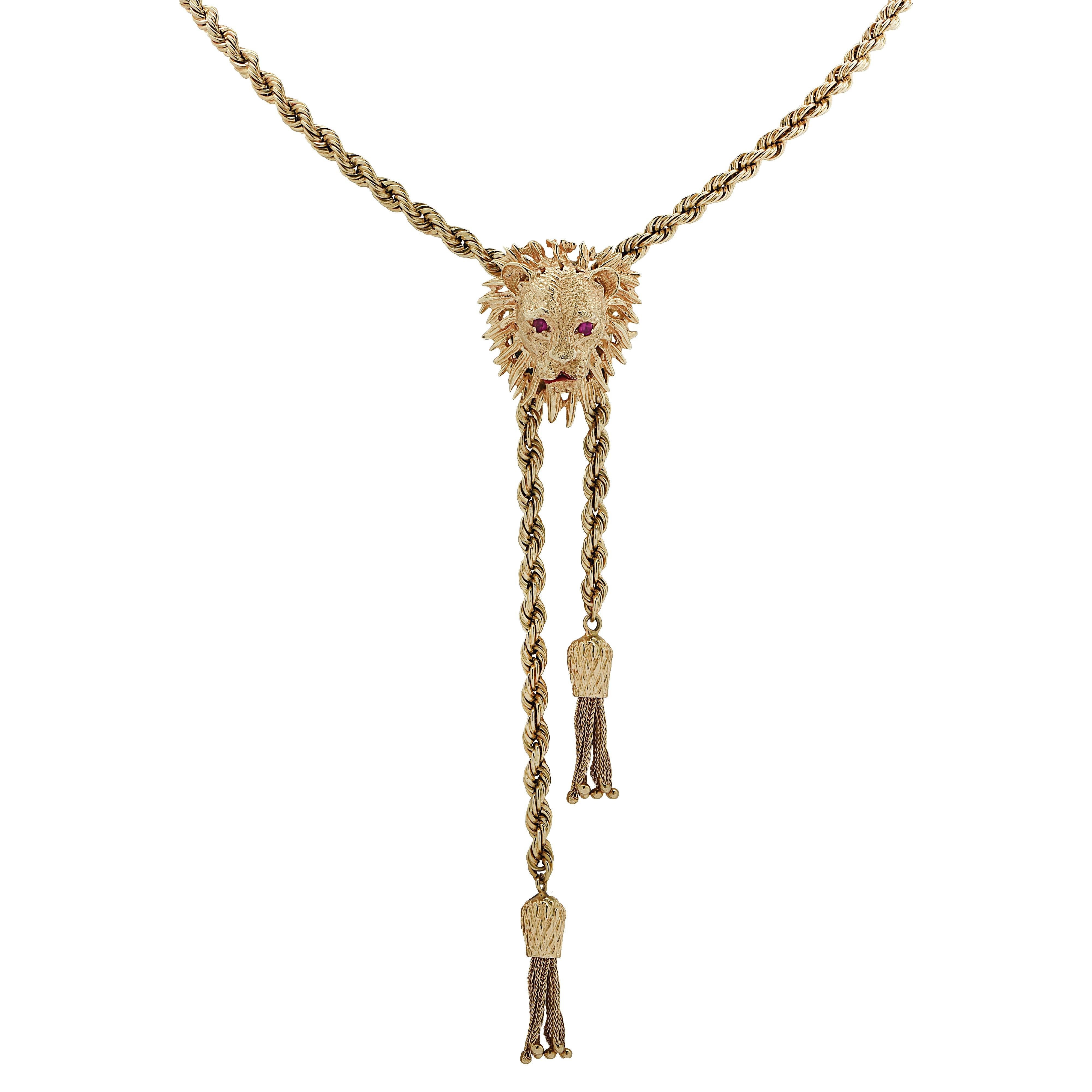 Regal yellow gold lariat necklace crafted in yellow gold showcasing an intricately crafted Lion’s Head with ruby eyes and a red enamel mouth. Twisted gold rope chain detailed with yellow gold tassels, threads through the back of the Lion’s Head. The
