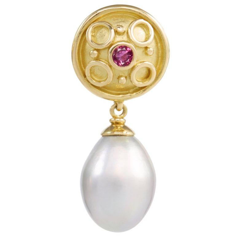 These striking earrings are inspired from ancient styles. 18 carat yellow gold with circles of gold and granulation on a shield with a central ruby set and freshwater pearl drops. With post and butterfly fittings.  Please note this item is made to