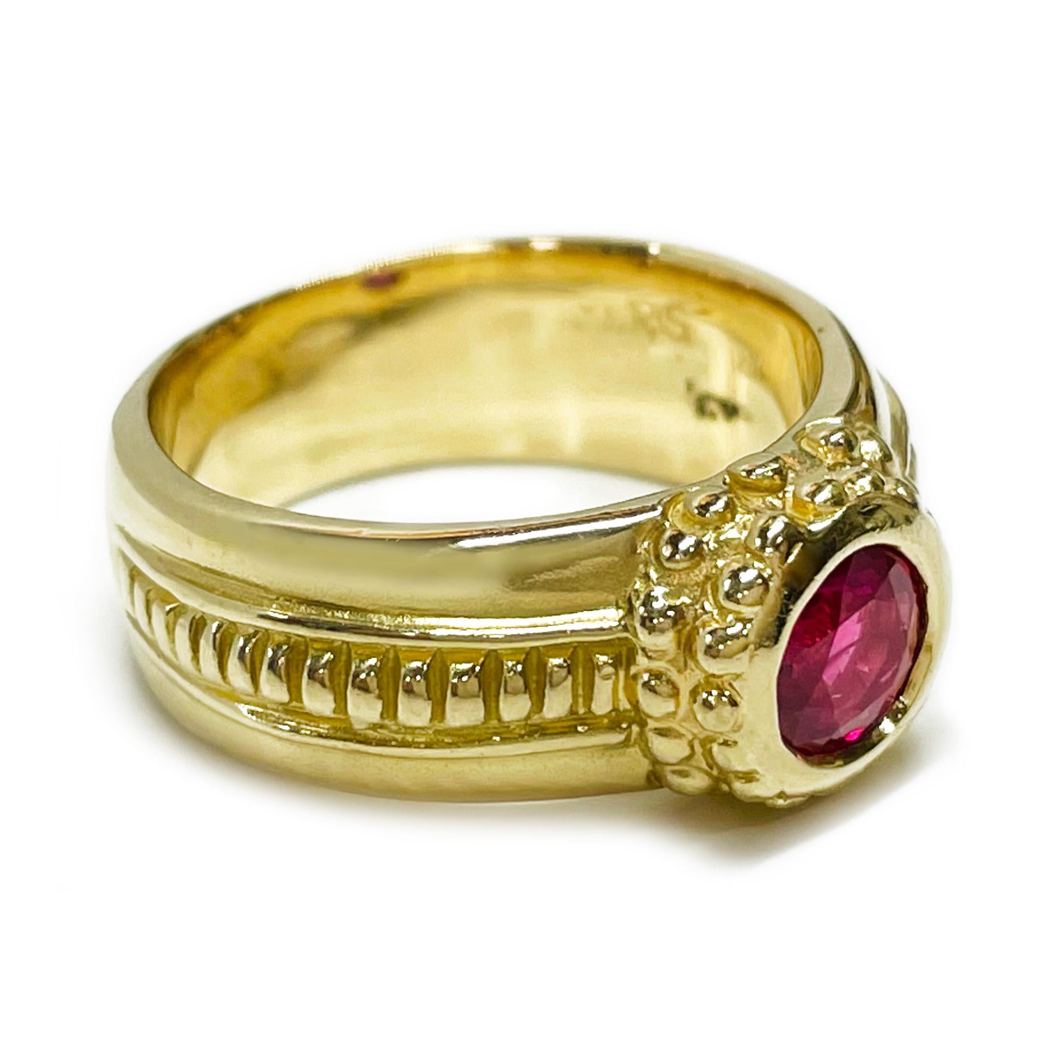 18 Karat Yellow Gold Ruby Ring. The ring features a single round bezel-set Ruby with an approximate carat weight of 0.80ct. The fancy band measures 6.6mm wide with gold beads around the center bezel and gold ridges on the side of the band. Stamped