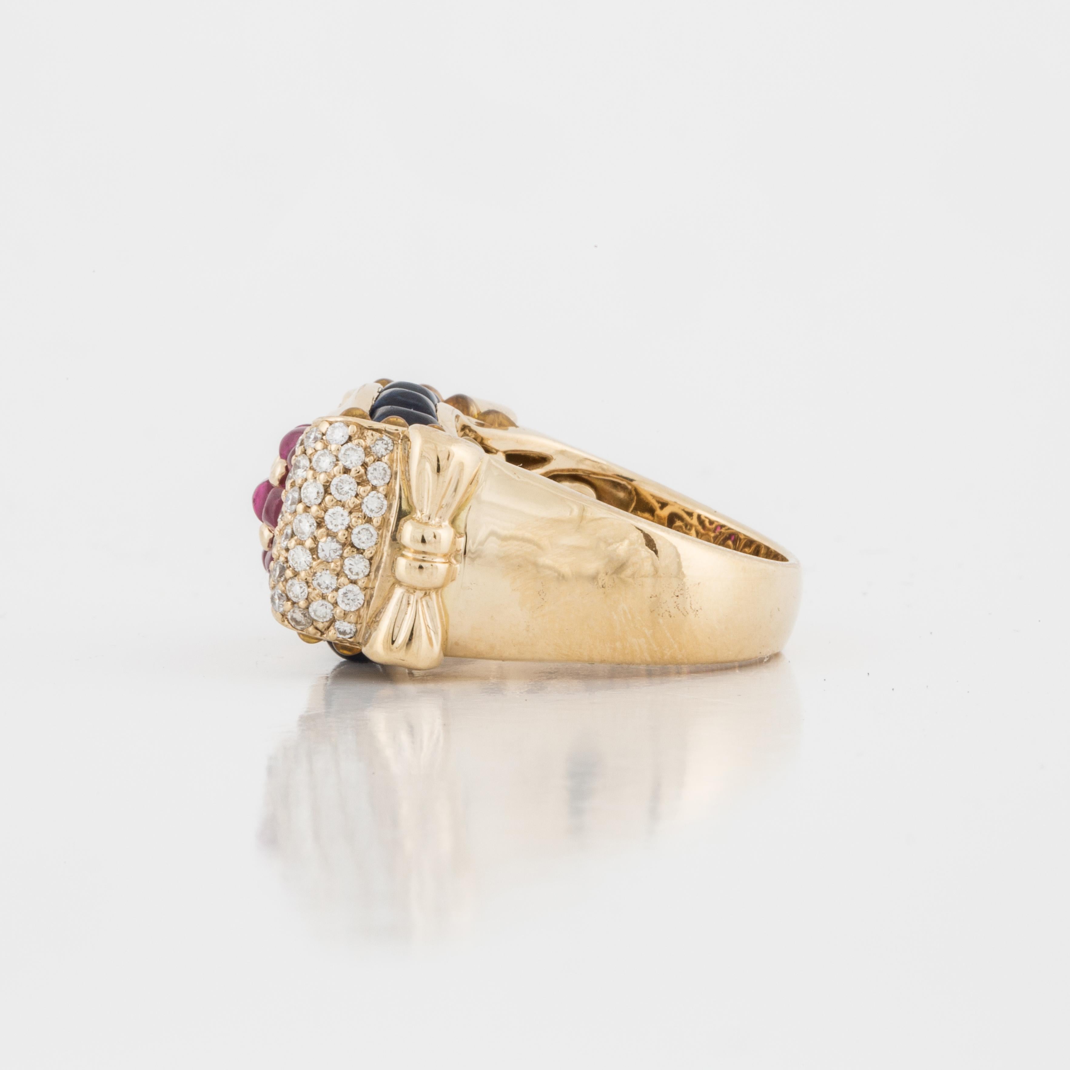 18K yellow gold ring featuring cabochon rubies with sapphire and diamond accents. This ring has twelve cabochon rubies that total 1.80 carats centrally featured with ten cabochon sapphires that total 1.90 carats on the sides of the ring with 60