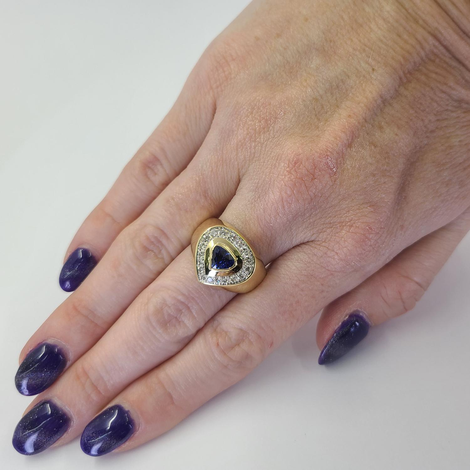18 Karat Yellow Gold Ring Featuring A Bezel Set Pear Shaped Sapphire Weighing Approximately 0.50 Carats Accented By 18 Round Brilliant Cut Diamonds of VS Clarity and H Color Totaling An Additional 0.50 Carats. Finger Size 8; Purchase Includes One