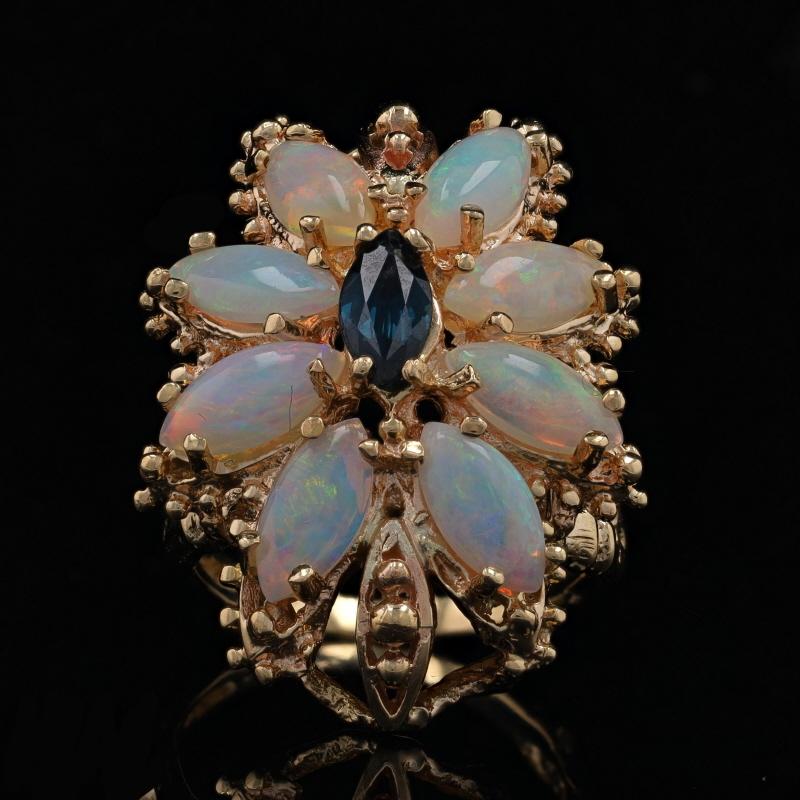 Size: 6 1/4
Sizing Fee: Up 2 sizes for $35 or Down 2 sizes for $30

Era: Vintage

Metal Content: 14k Yellow Gold

Stone Information
Natural Sapphire
Treatment: Heating
Carat(s): .60ct
Cut: Marquise
Color: Blue

Natural Opals
Carat(s): 3.60ctw
Cut: