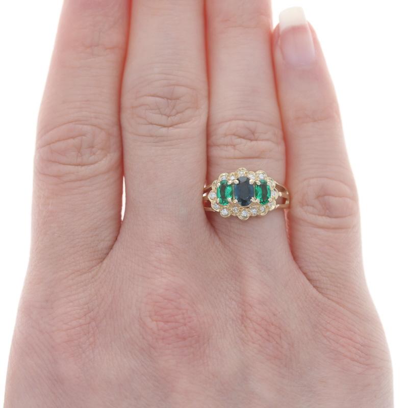 Yellow Gold Sapphire Synthetic Emerald Diamond Three-Stone Ring 14k Lab-Created

Stone Information:
Natural Sapphire
Treatment: Heating
Carat(s): .60ct
Cut: Oval
Color: Blue

Synthetic Emeralds
Carat(s): .50ctw
Cut: Oval
Color: Green

Natural