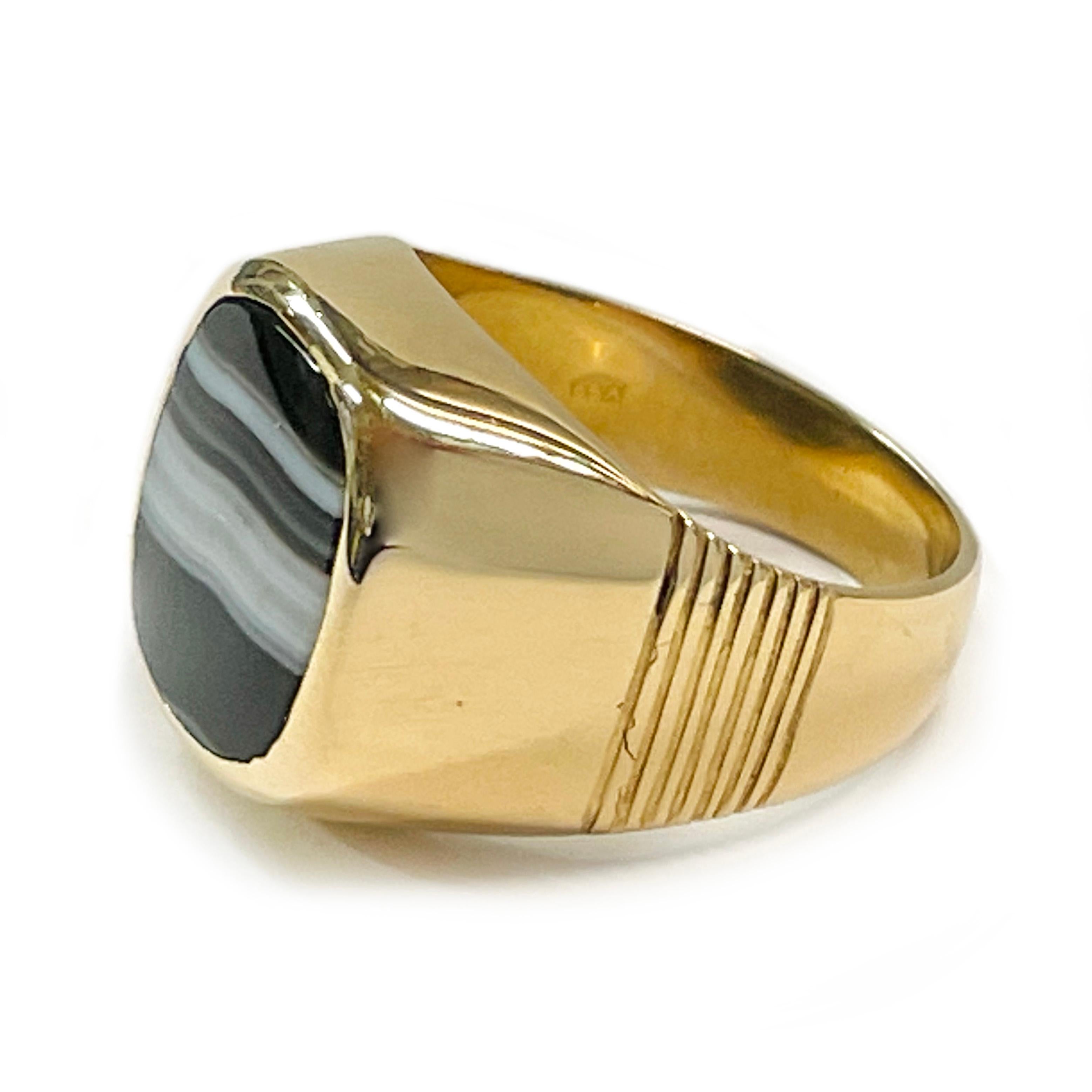18 Karat Yellow Gold Sardonyx Ring. The wide band ring features a striped white, gray, and black sardonyx rounded rectangular stone. The sardonyx stone measures 13.3mm x 11.5mm. The band has light grooves about mid-way on each side of the tapered