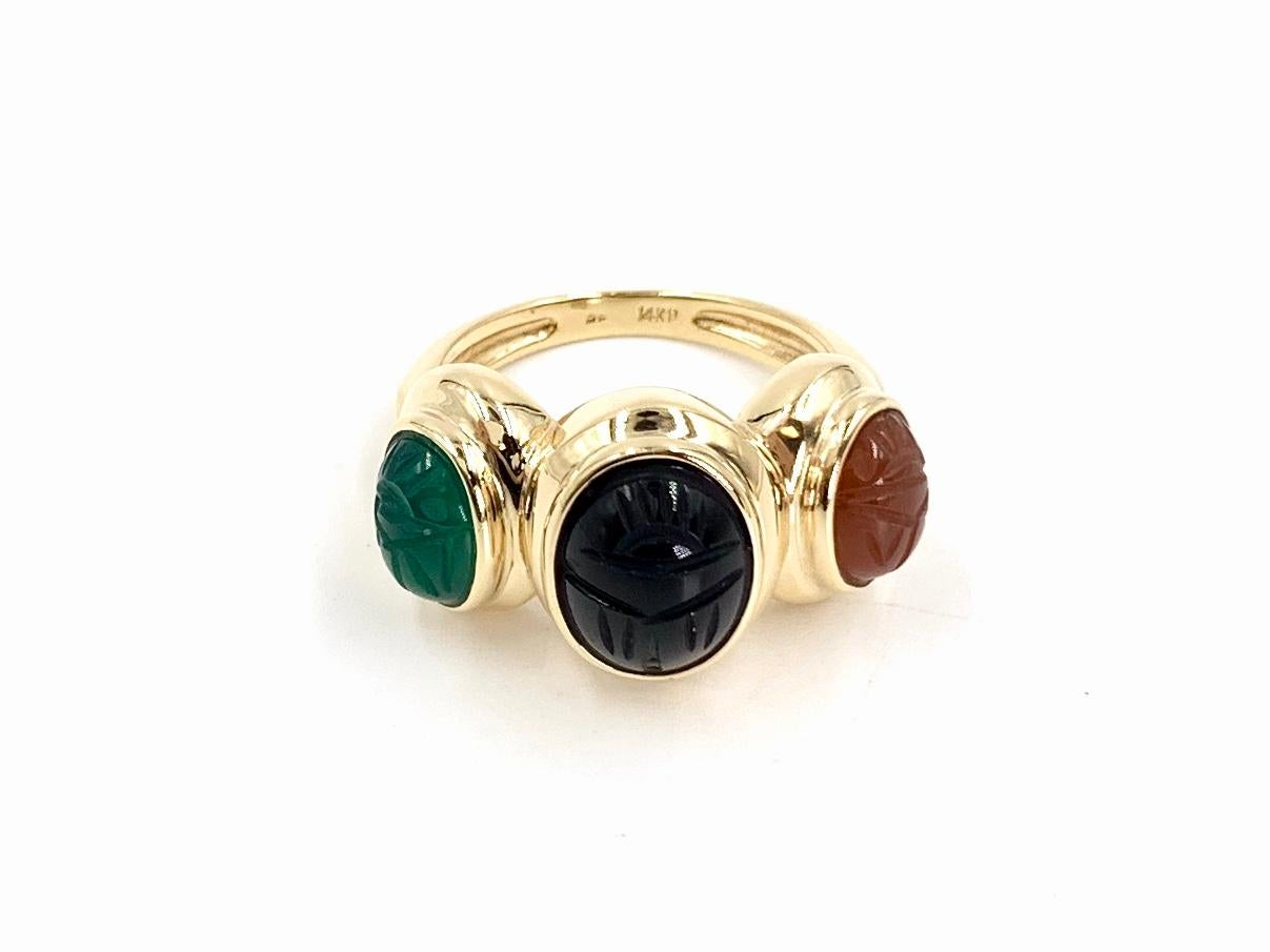 A well made, polished 14 karat yellow gold three oval stone style scarab ring featuring hand carved deep green chrysoprase, black onyx and burnt orange carnelian. Stones are securely set in bezels. Width of ring measures 1/2