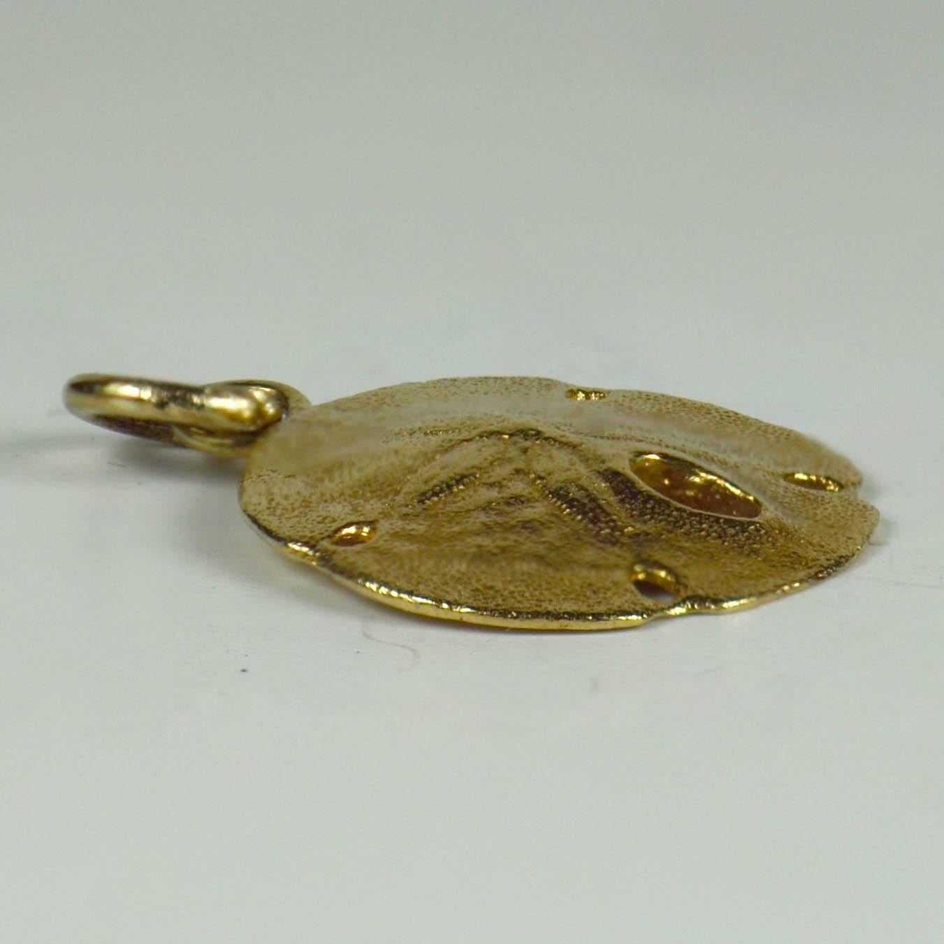 A 14 karat yellow gold charm pendant designed as a three dimensional sand dollar - a member of the sea urchin family. 
Marked 14K.

Dimensions: 2.2 x 1.6 x 0.3 cm
Weight: 2.07 grams.