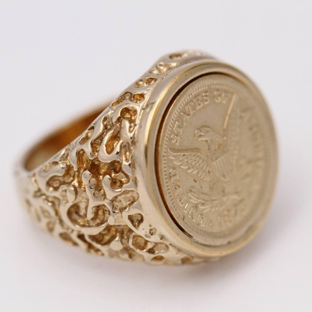 Gold Seal for men set with a 1873 United States of America coin  18kt Yellow Gold  13.44 grams.  The central coin measures 18mm  Size 16,5  This ring is in excellent condition with no visible wear and tear  Ref: D359546JC