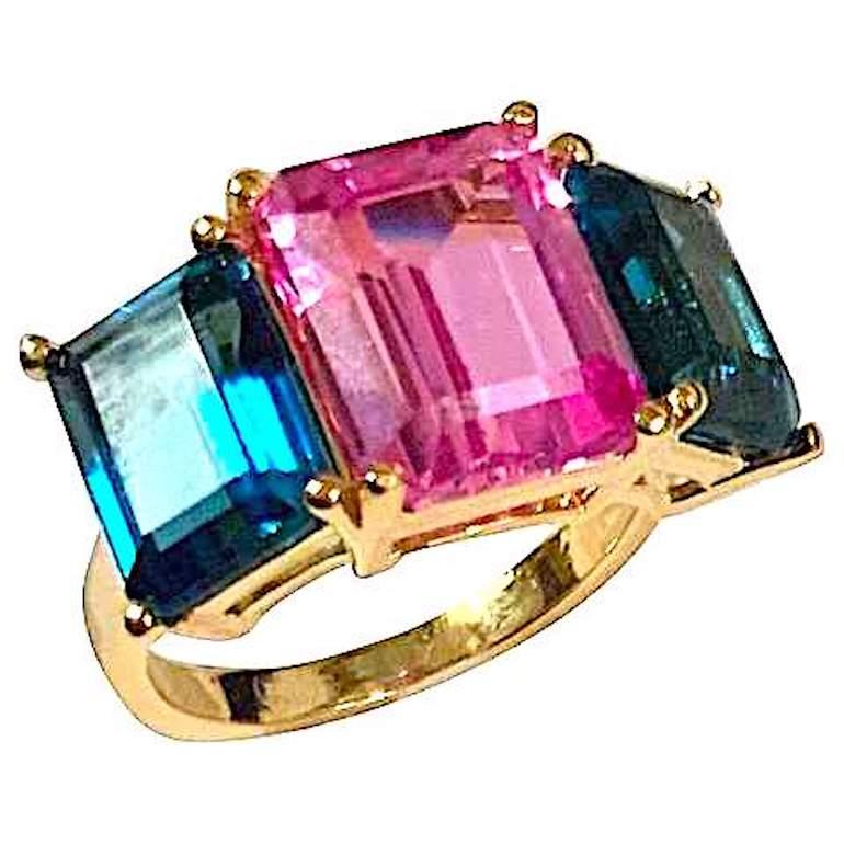 18kt Yellow Gold Mini Emerald Cut Ring with Pink Topaz Center and and Peridot Side stones

The ring Measures approximately 3/4 inch across and 1/2 high.

This mini emerald cut ring can be made in any ring size and with any colored semi precious