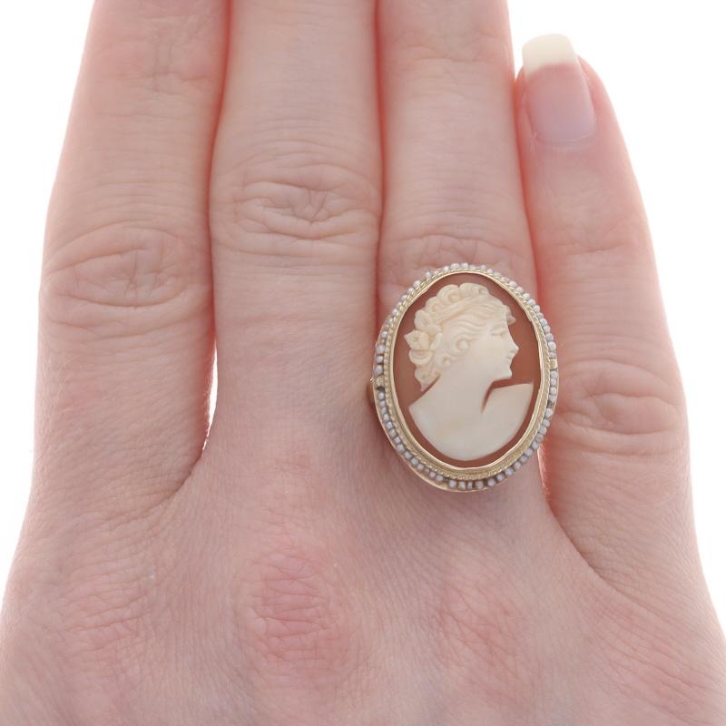 Size: 6 1/2
Sizing Fee: Up 2 sizes for $35 or Down 1 size for $30

Era: Vintage

Metal Content: 14k Yellow Gold

Stone Information
Natural Shell
Cut: Carved Cameo
Size: (approx.) 19.6mm x 14.4mm

Natural Seed Pearls

Style: Halo Cameo
Theme: