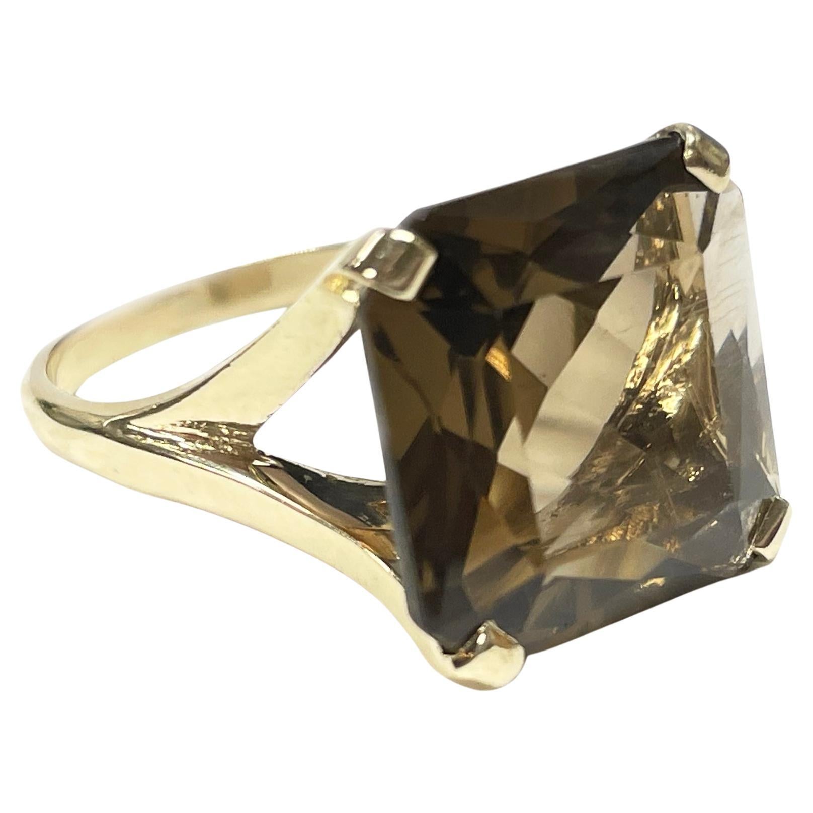 10 Karat Yellow Gold Smoky Quartz Ring. The ring features a 14mm square bezel-set step-cut Smoky Quartz. The split band tapers and has a smooth shiny finish. Stamped on the inside of the band is 10K SPRI, the rest of the letters are worn off. The