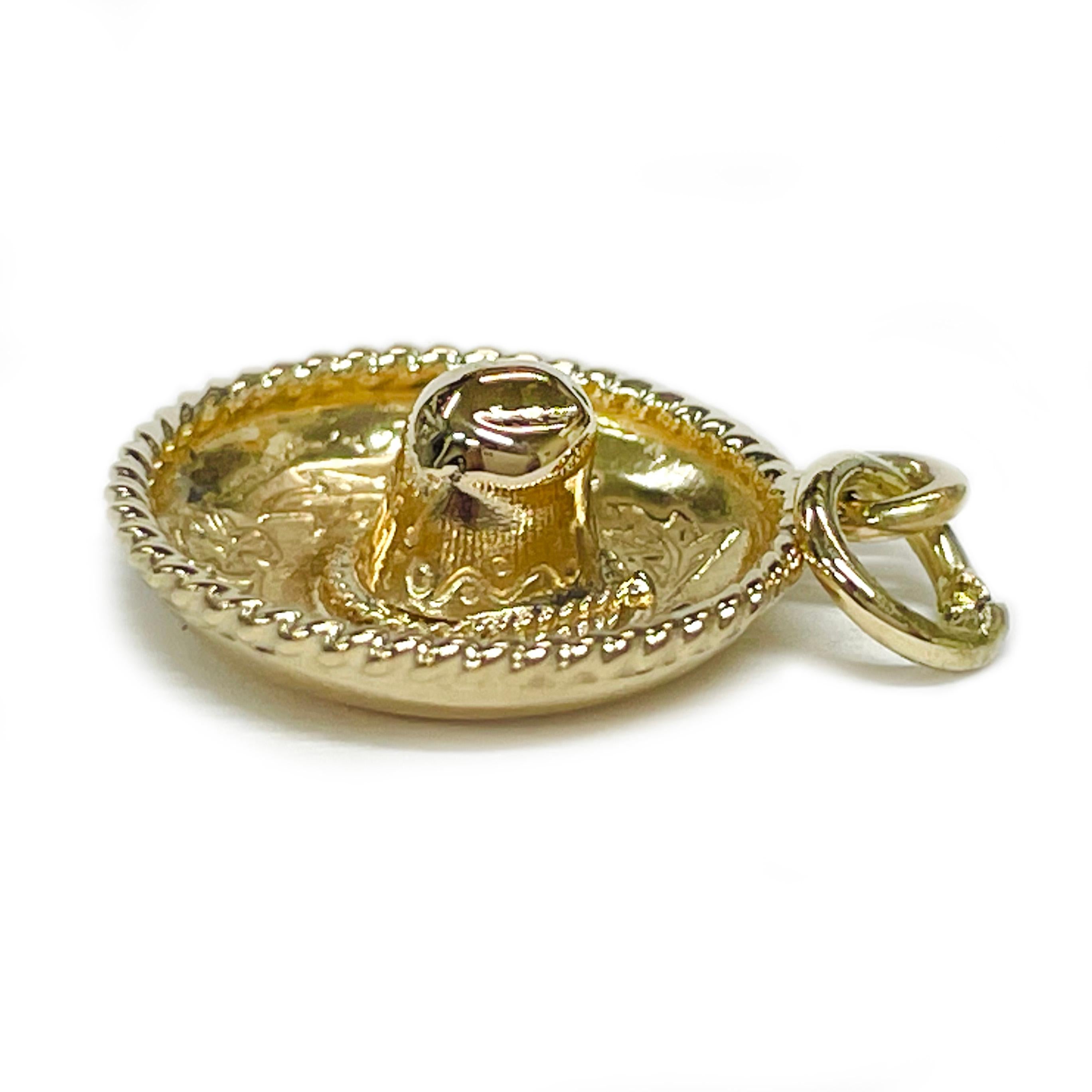 Ce charmant pendentif sombrero en or jaune 14 carats est un ajout délicieux à toute collection de bijoux. De petite taille, il est orné de fleurs et de feuilles complexes le long du bord, accentuées par une délicate bordure en corde qui ajoute de la
