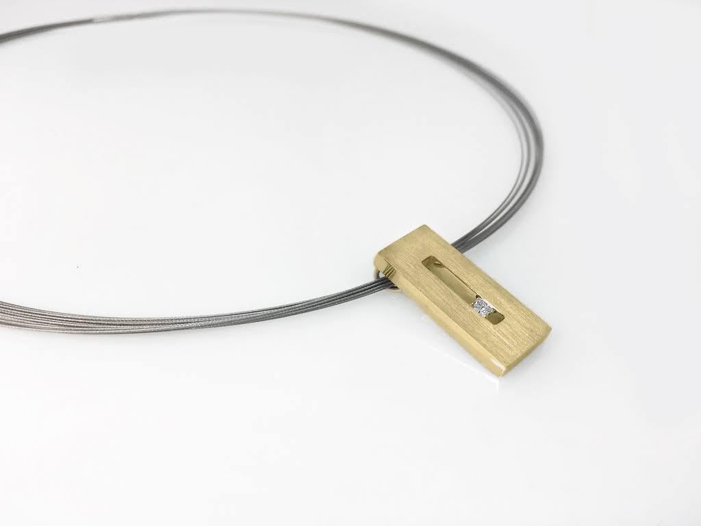 This Diamond in Yellow Gold Suspended Rectangle Pendant is part of our Suspension Collection. Modern and architecturally inspired, this rectangle pendant is shown in yellow gold with a brushed finish and set off center with an approximately .13pts