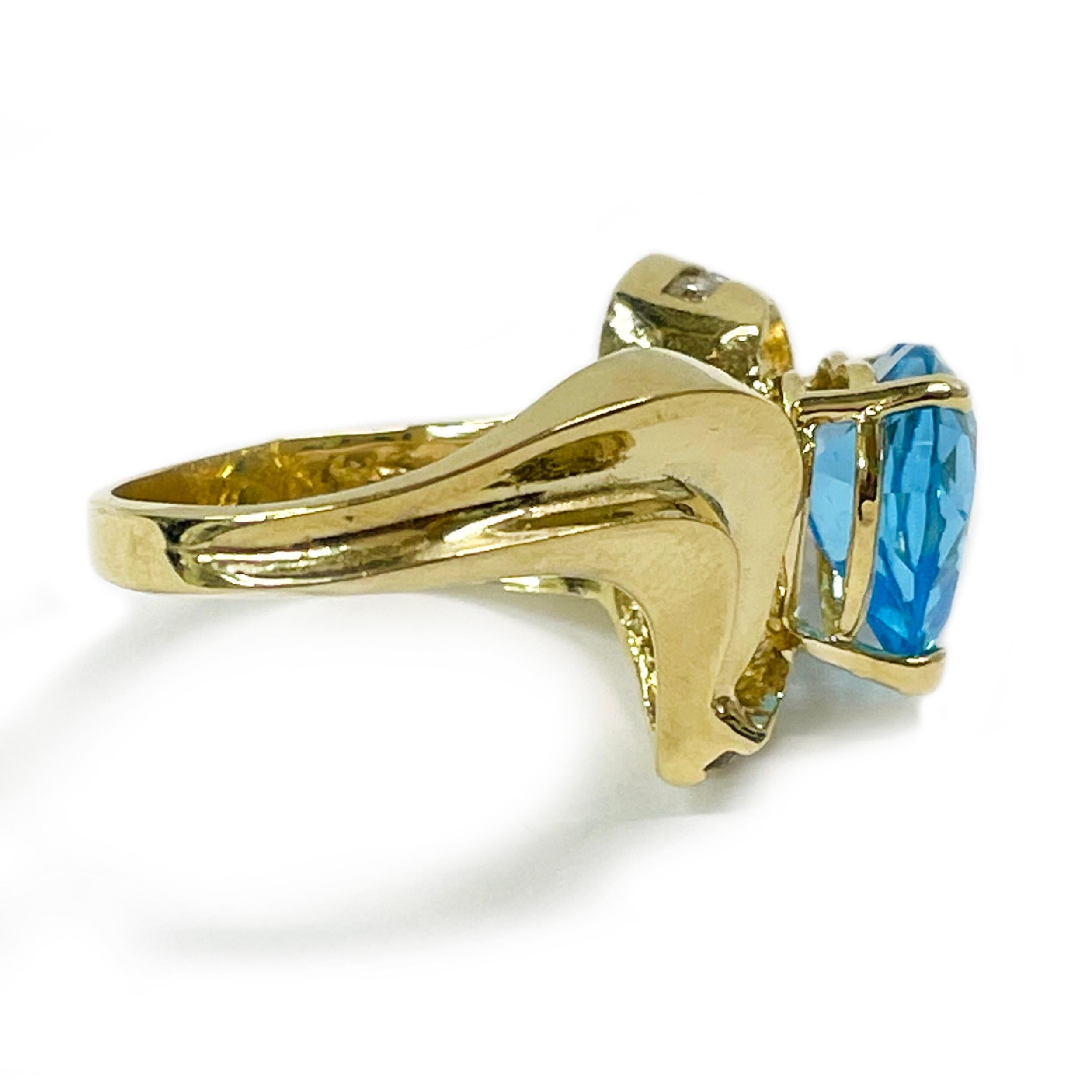 14 Karat Yellow Gold Swiss Blue Topaz Heart Diamond Ring. The ring features a 10 x 9.5mm heart-shaped Swiss Blue Topaz three-prong set on a raised gallery. Eleven round diamonds are channel-set on one side on a curved gold shape. The diamonds are