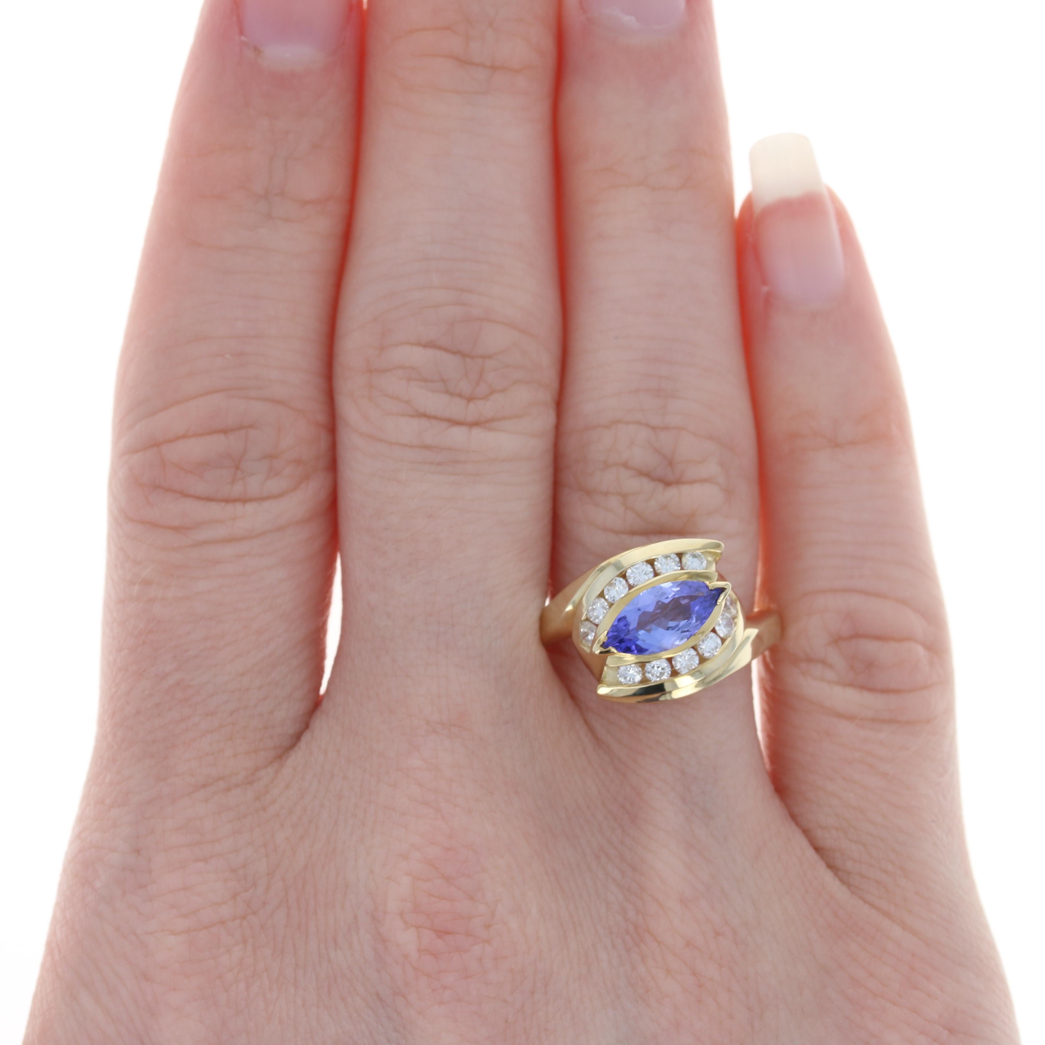 Beautifully crafted in 14k yellow gold, this bypass-style ring showcases a satiny purple tanzanite that is highlighted by a shimmering swirl of icy white diamond accents set around the solitaire. This radiant piece would also make a cherished