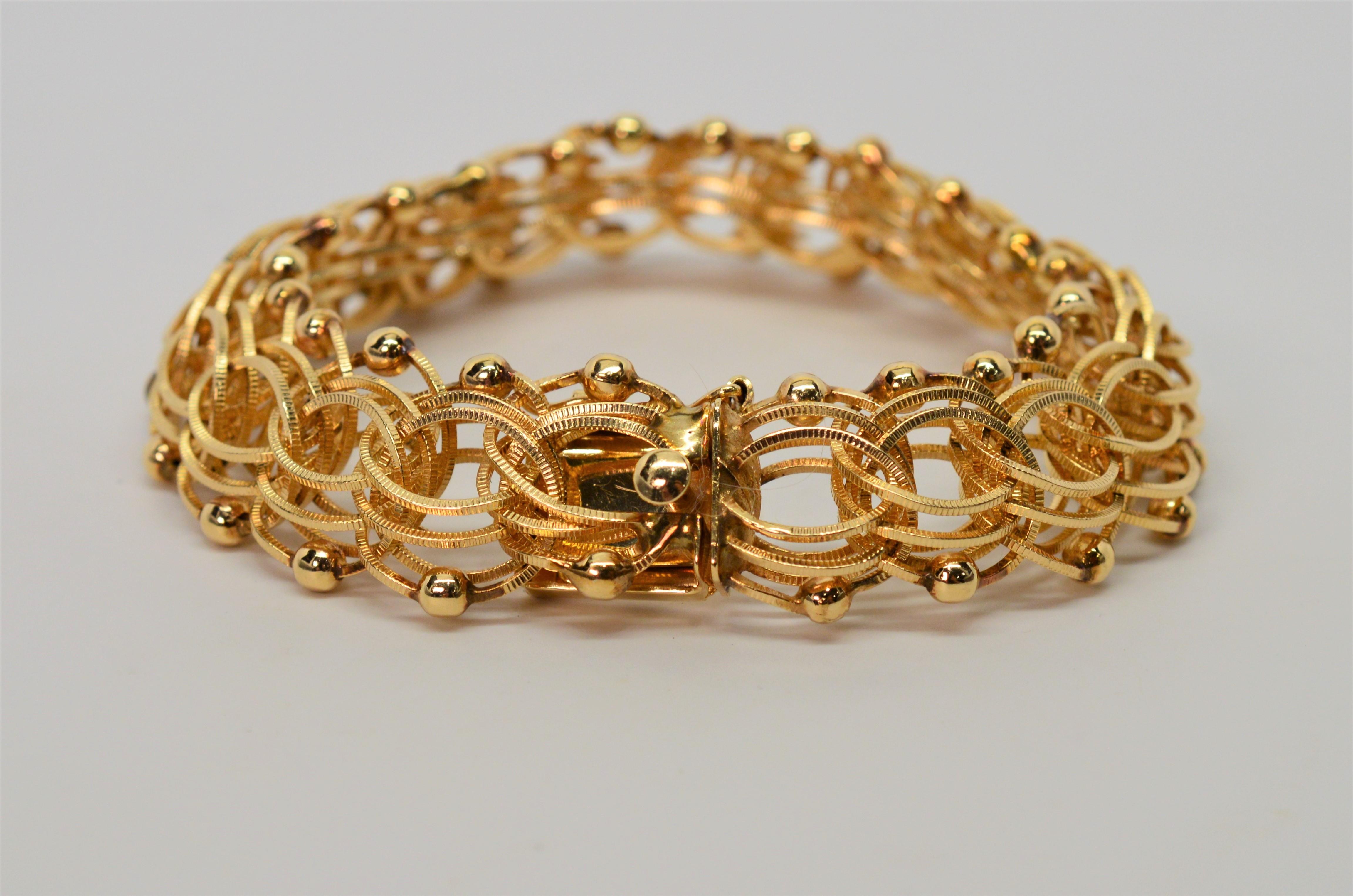 Finely crafted circa 1950's, this eight inch bracelet made of fourteen karat 14K yellow gold is constructed of uniquely intertwined textured center chain links accented by a border of bright gold polished beads resulting in a beautiful textured